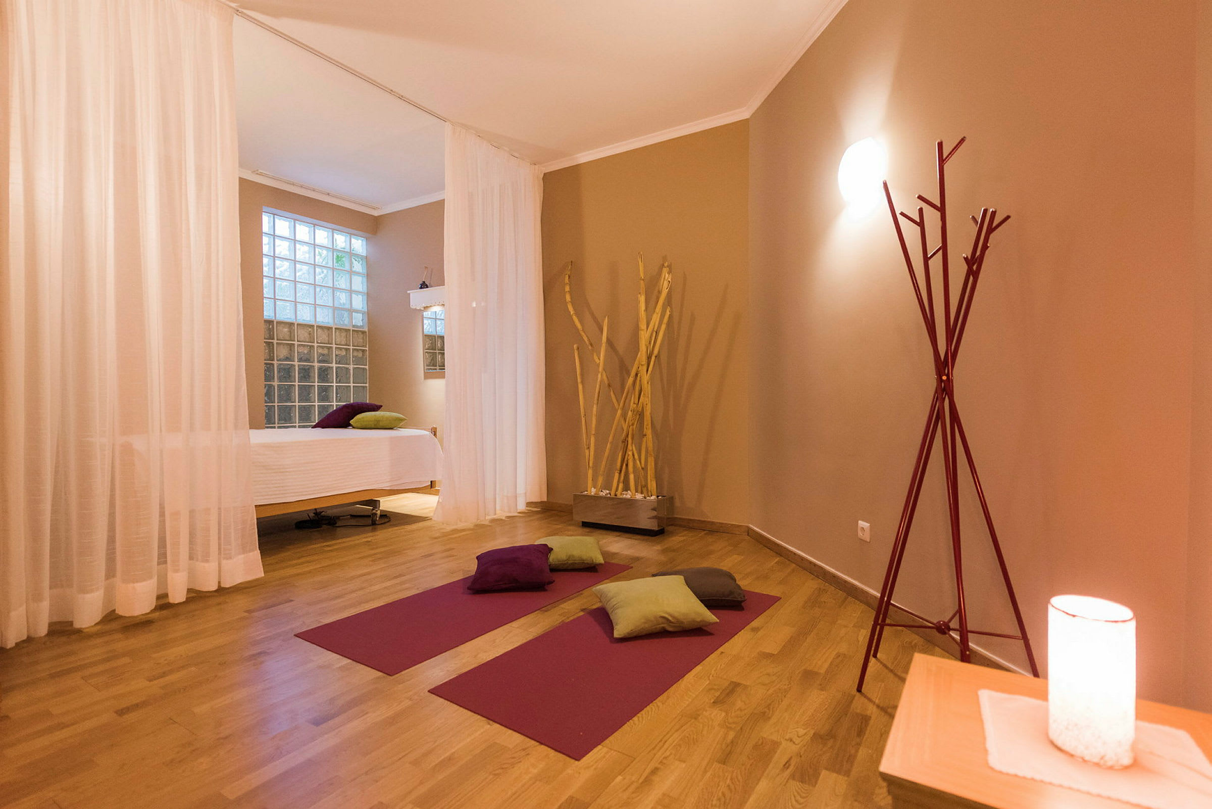 Et yogarum med måtter, puder og en massagebriks, indrettet med varme farvetoner. (AI-genereret tekst)