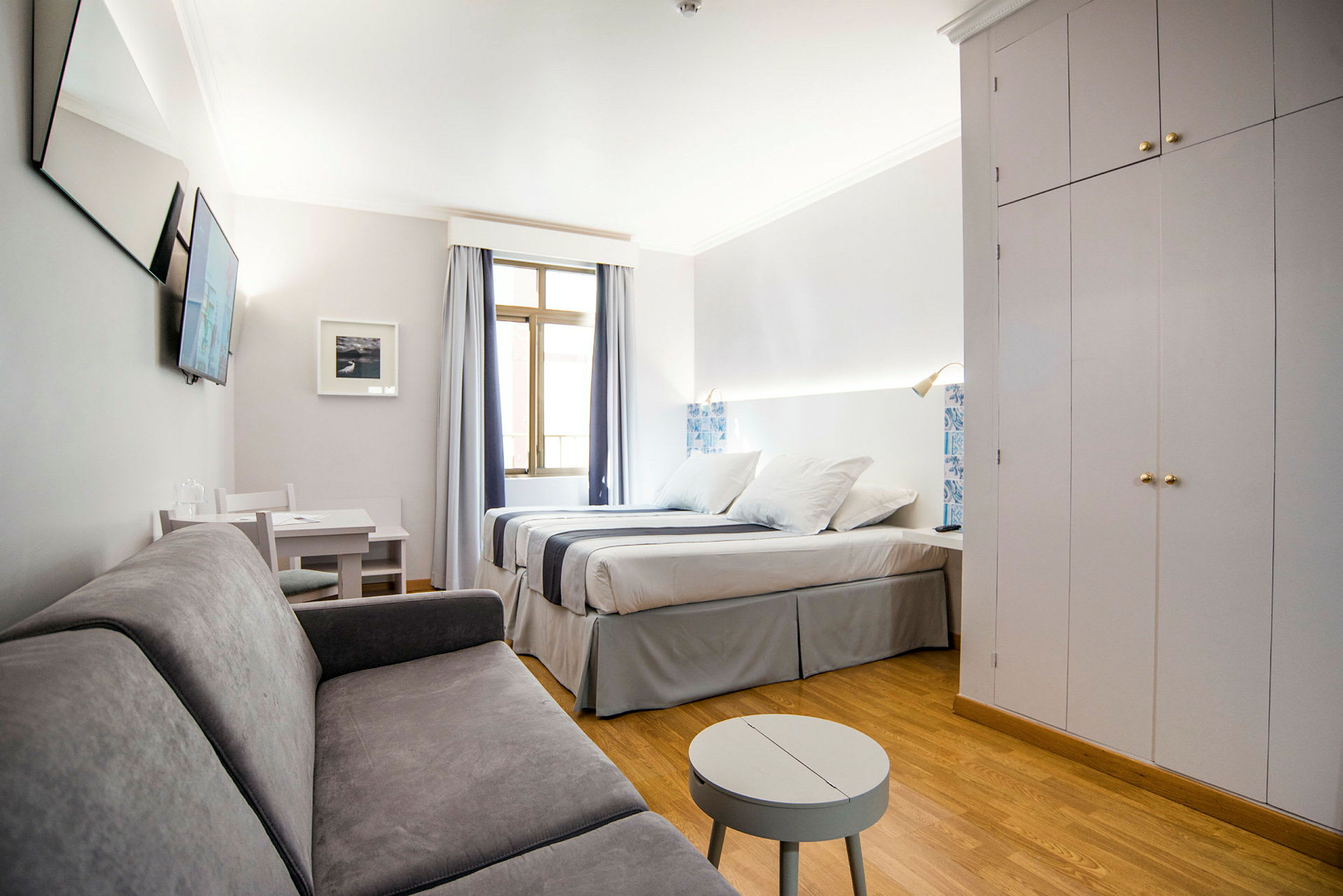 Hotelværelse med dobbeltseng, sofa, bord og skab. (AI-genereret tekst)