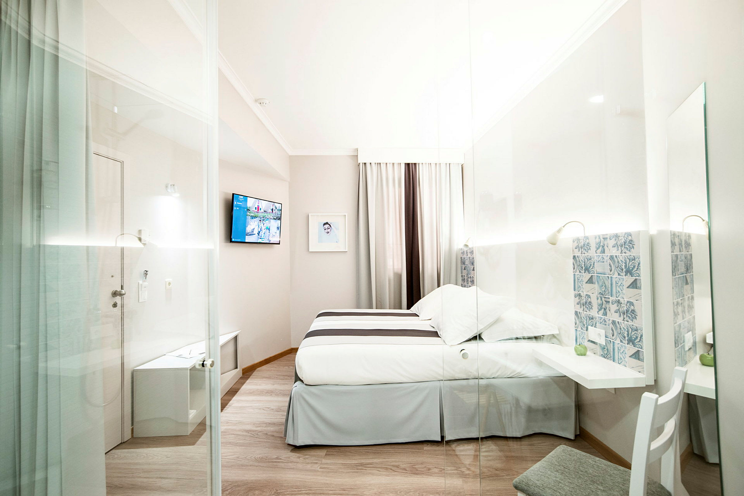Moderne hotelværelse med seng, tv og glasvæg. (AI-genereret tekst)