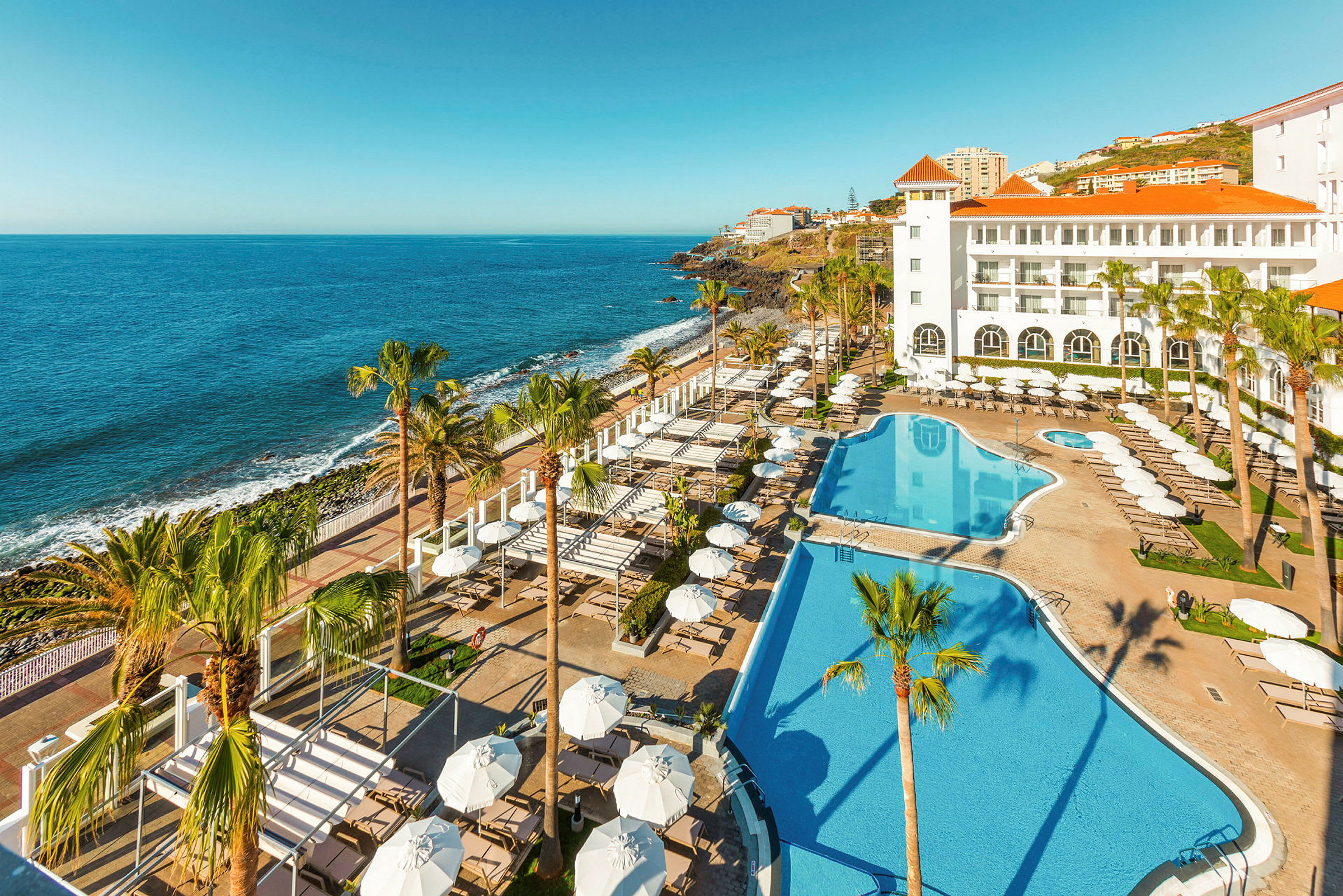 Hotel med poolområde og udsigt over havet. (AI-genereret tekst)