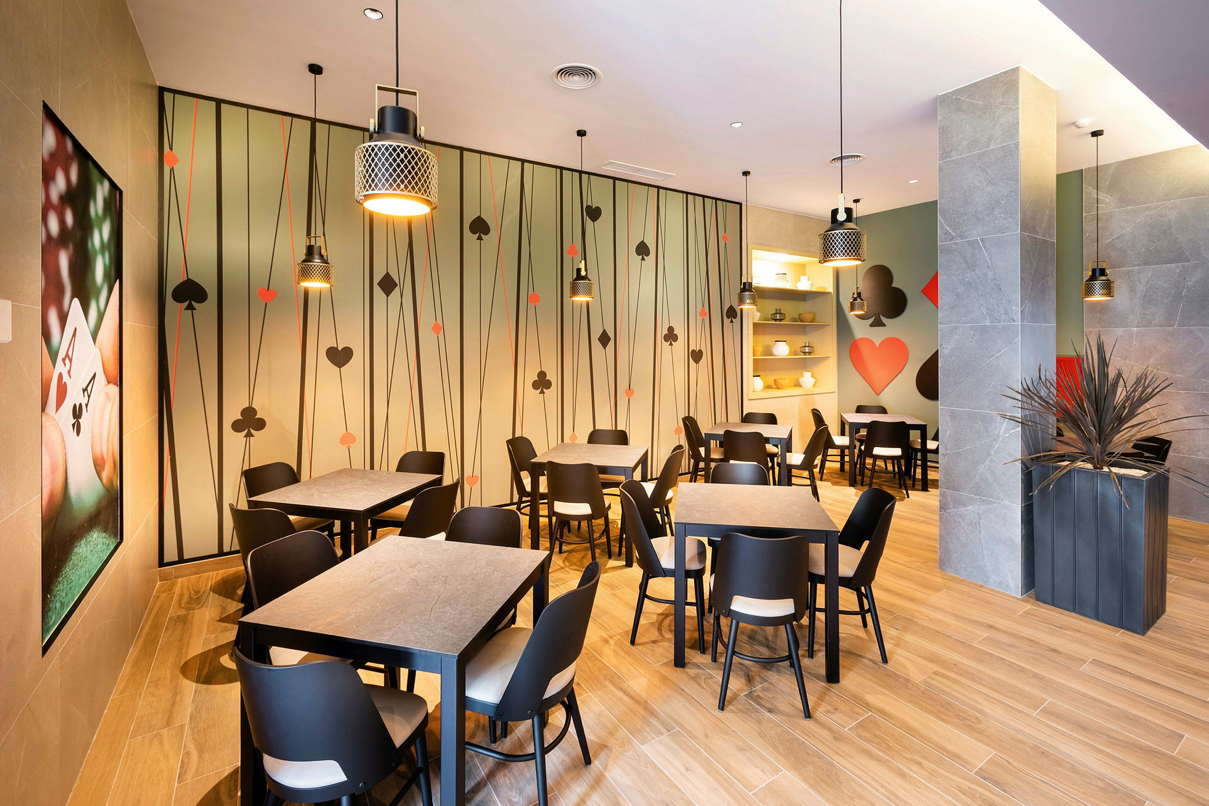 Billede af en restaurantindretning med spillekorttema, siddeområder og vægdekorationer. (AI-genereret tekst)
