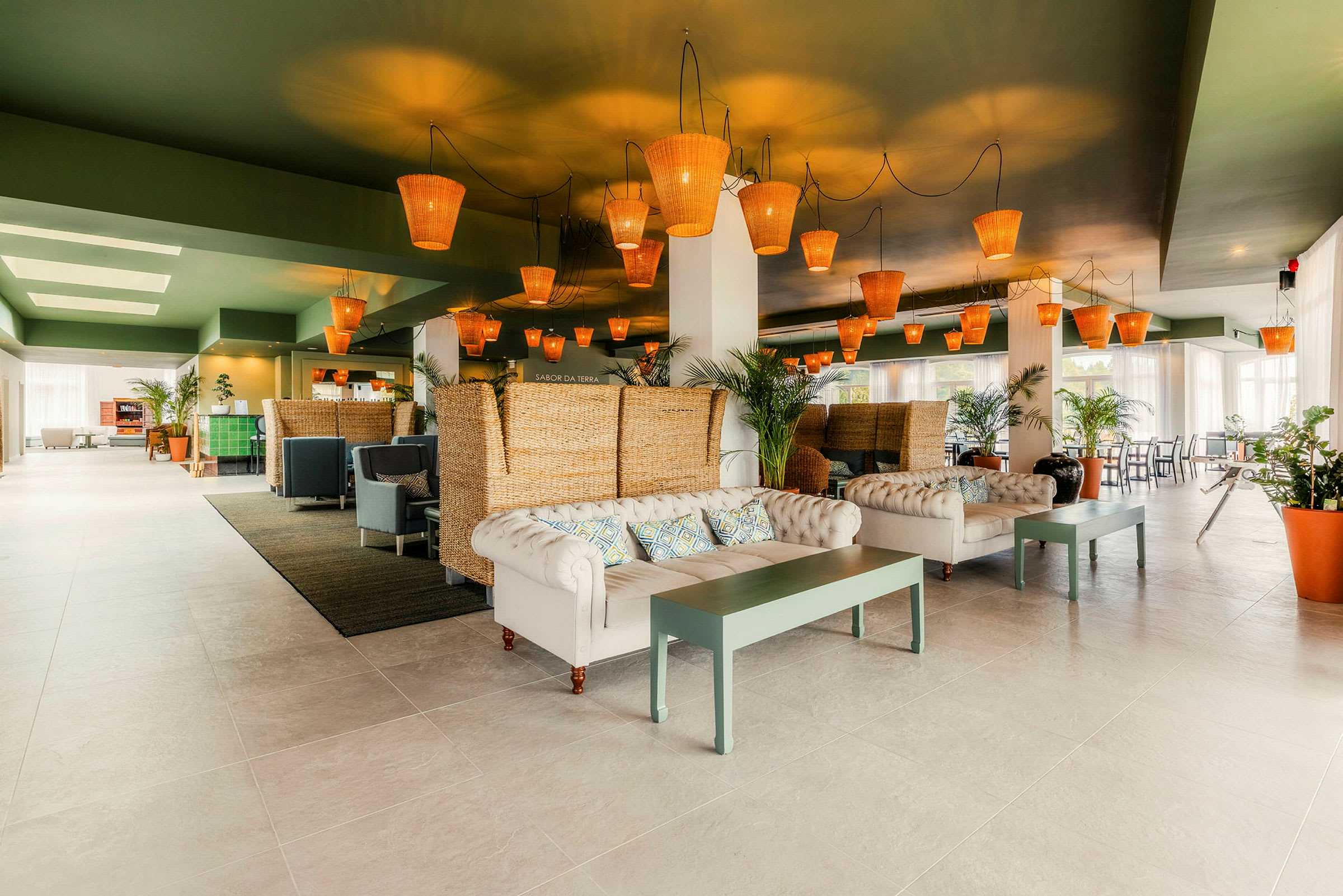 En moderne og elegant lobby med sofaer, borde og rottinglamper i loftet. (AI-genereret tekst)