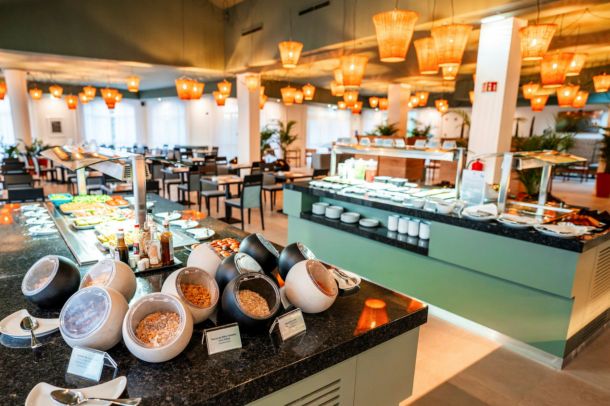 Morgenmadsbuffet med forskellige stationer og siddepladser i restaurantmiljø. (AI-genereret tekst)