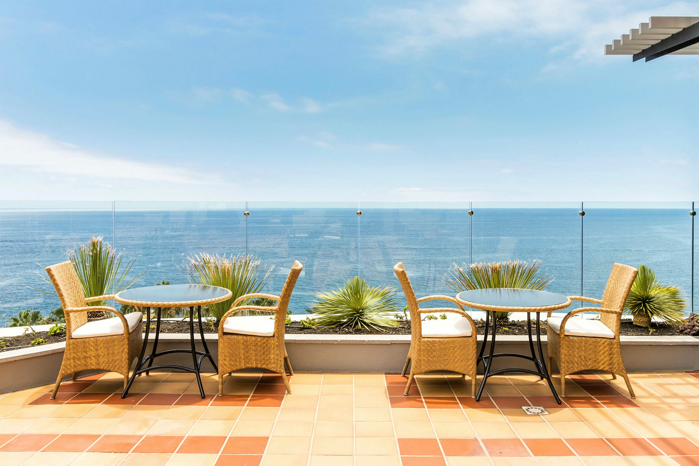 En terrasse med møbler i rattan og udsigt over havet. (AI-genereret tekst)