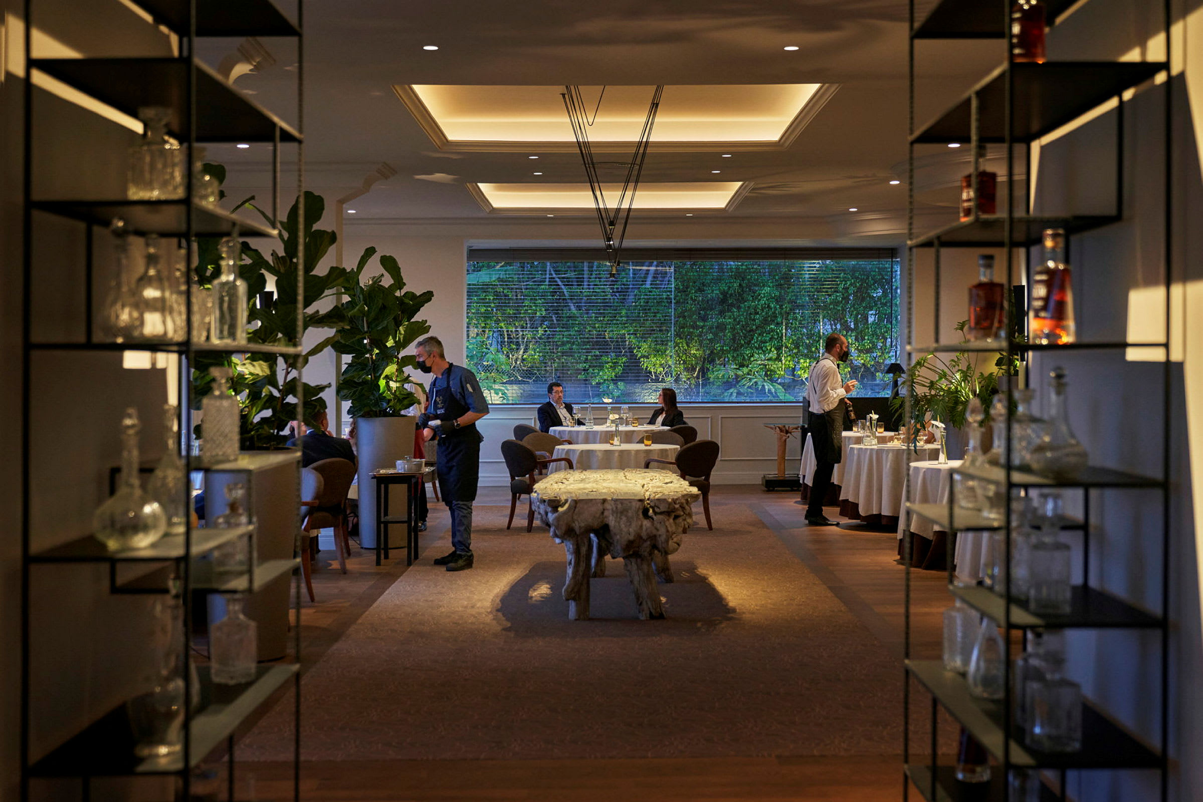 Restaurantmiljø med borde, stole og planter. (AI-genereret tekst)