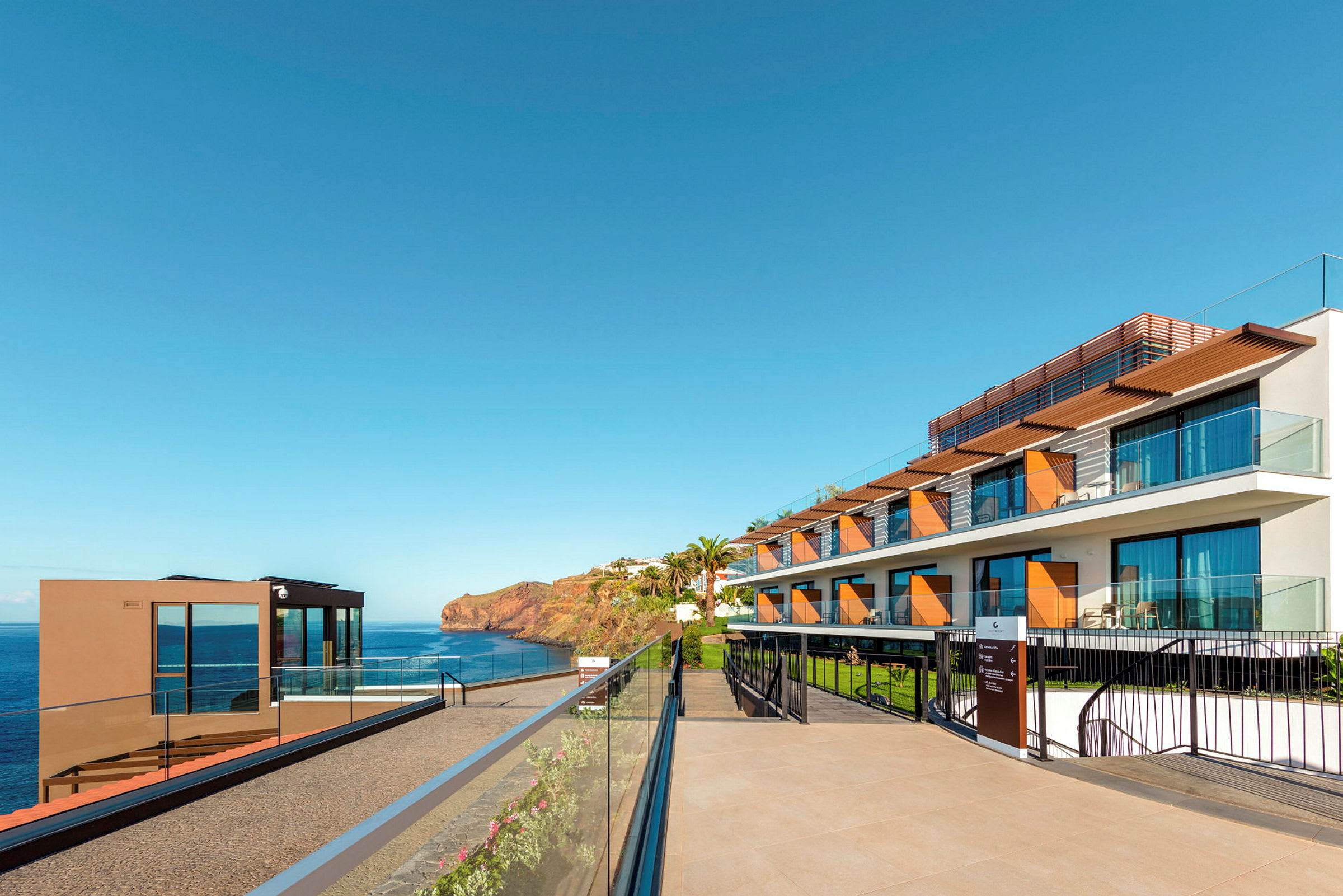 Hotelbygning ved havet under en klar blå himmel. (AI-genereret tekst)