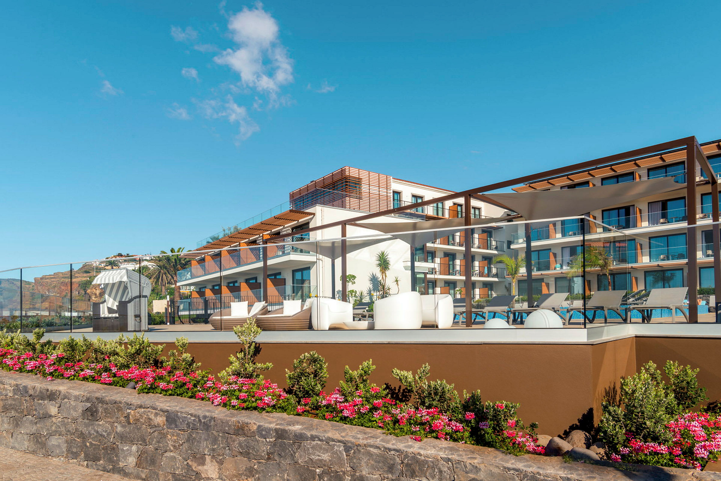 Moderne hotel med poolområde og blomster i forgrunden. (AI-genereret tekst)