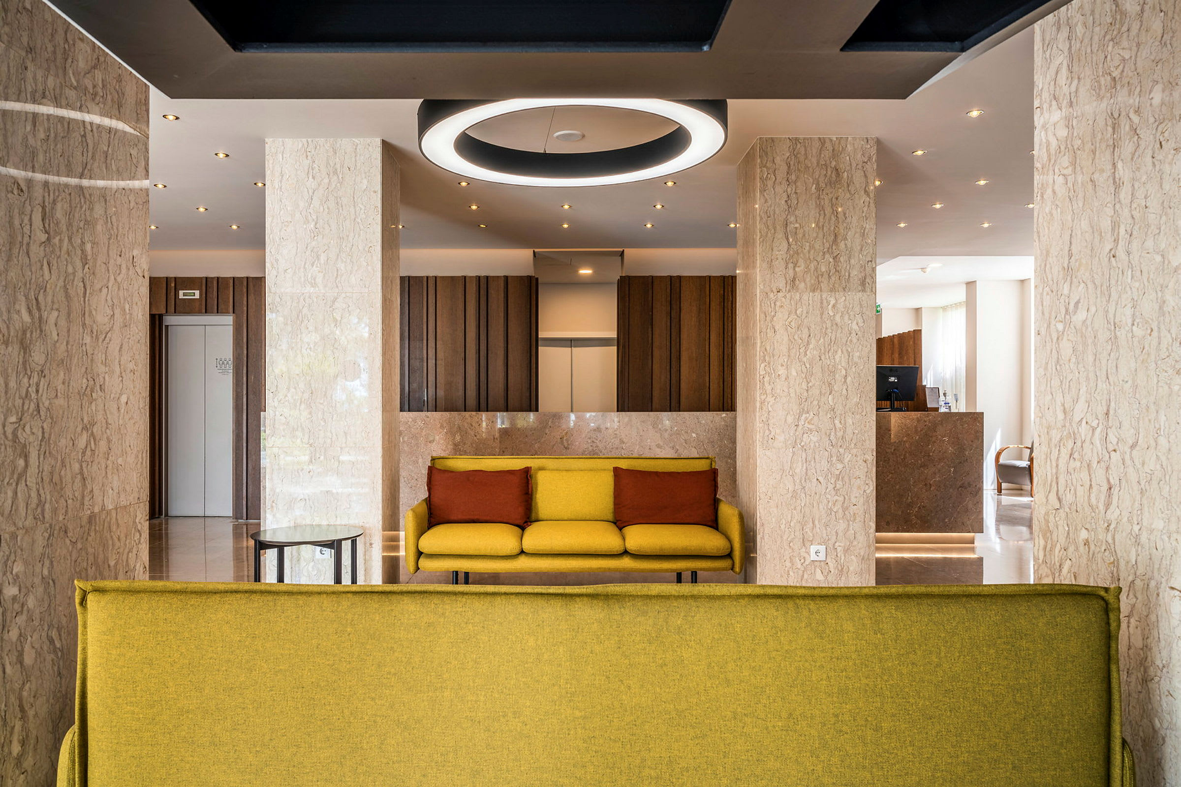 Moderne hotellobby med gule sofaer og marmorgulve. (AI-genereret tekst)