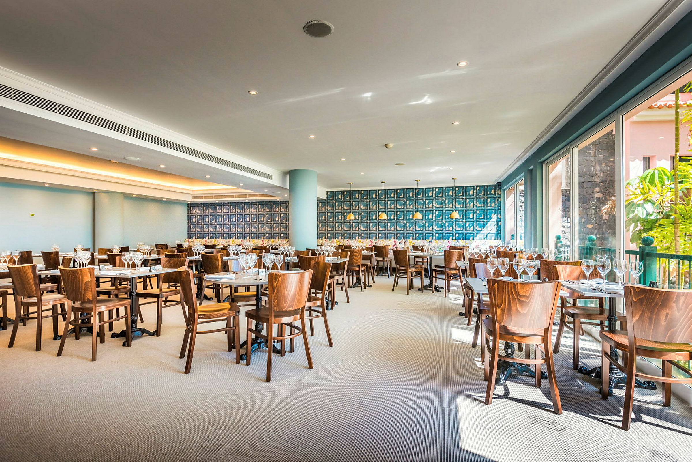En restaurant med borde og træstole, dekoreret med flere vinglas. (AI-genereret tekst)