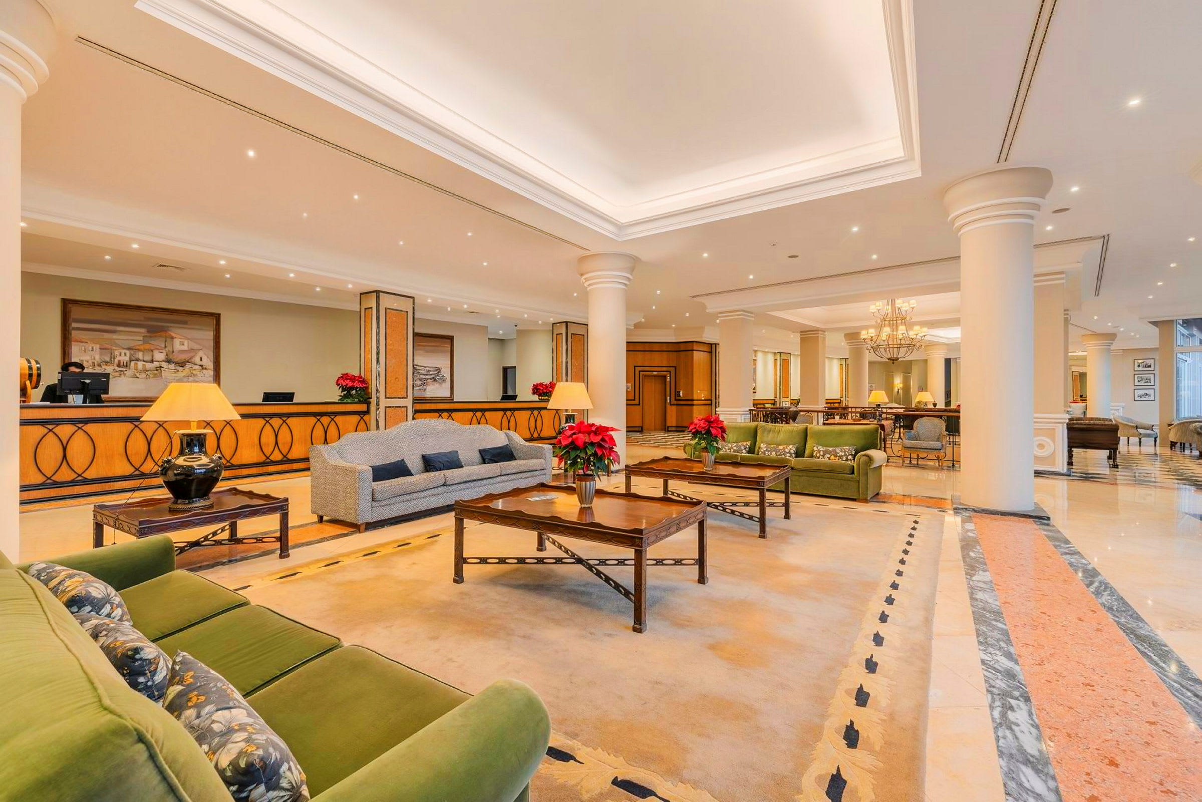 Et elegant hotellets lobbyområde med sofaer, borde, tæpper og dekorative planter. (AI-genereret tekst)