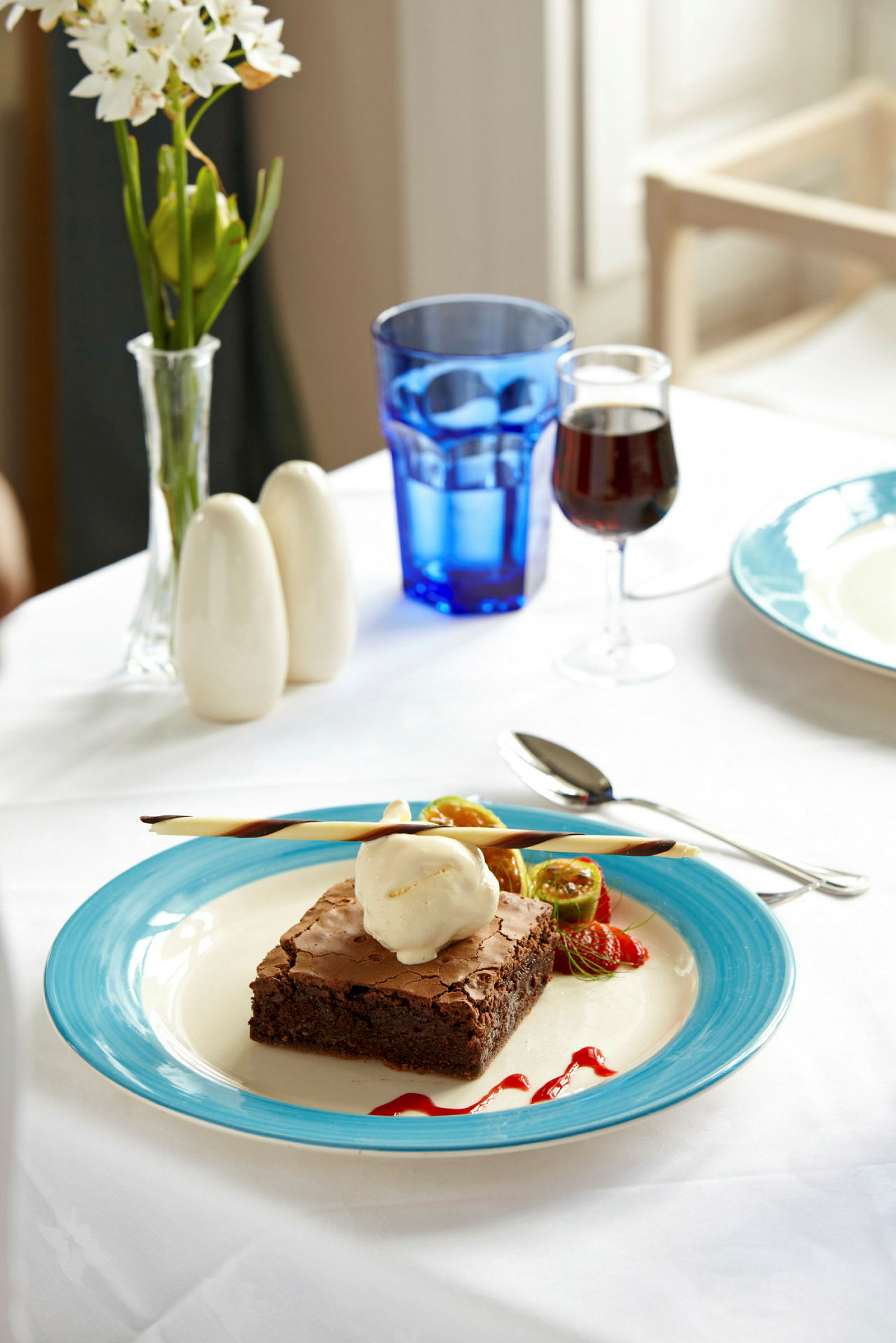 En tallerken med brownie og is, pyntet med frugt og sauce. (AI-genereret tekst)