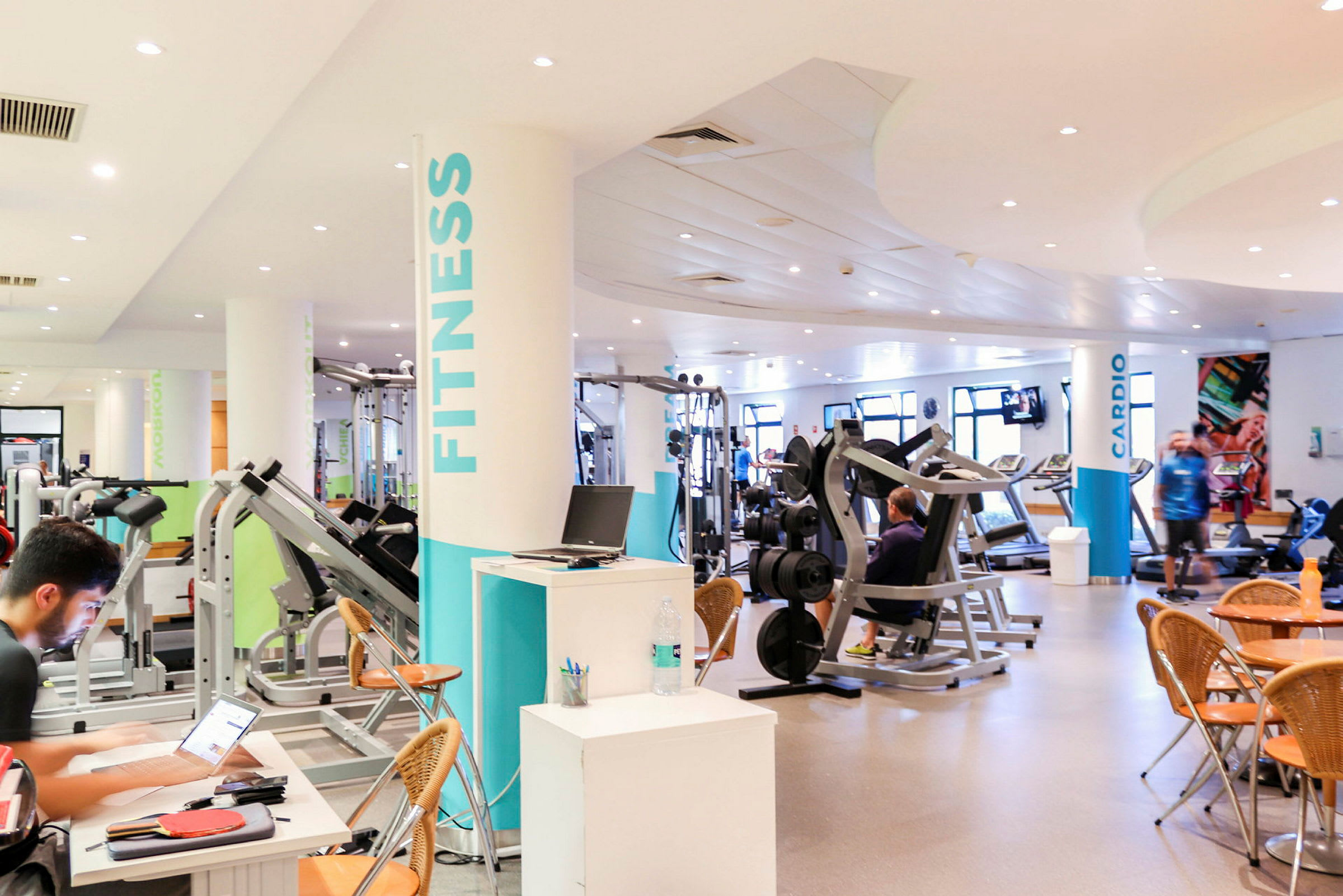 Fitnesscenter med træningsudstyr og siddepladser. (AI-genereret tekst)