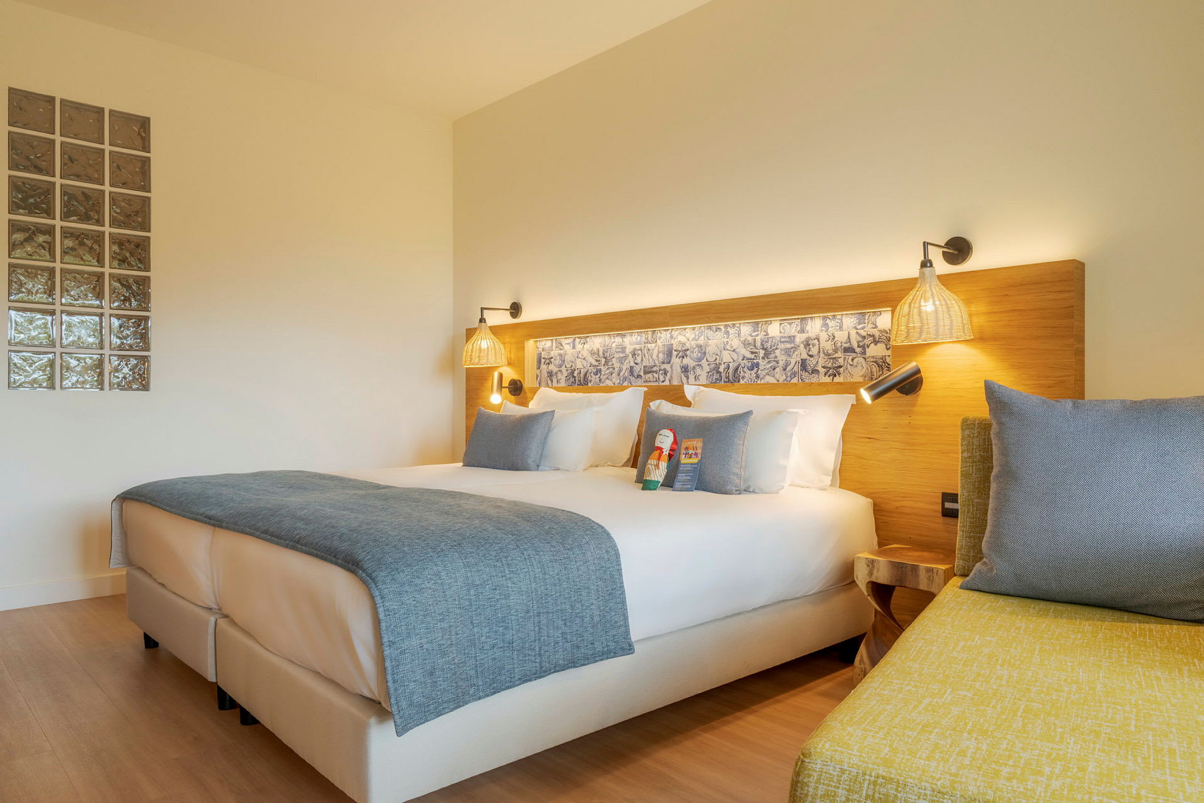 Moderne hotelværelse med dobbeltseng, hvidt sengetøj og blåt sengetæppe. (AI-genereret tekst)