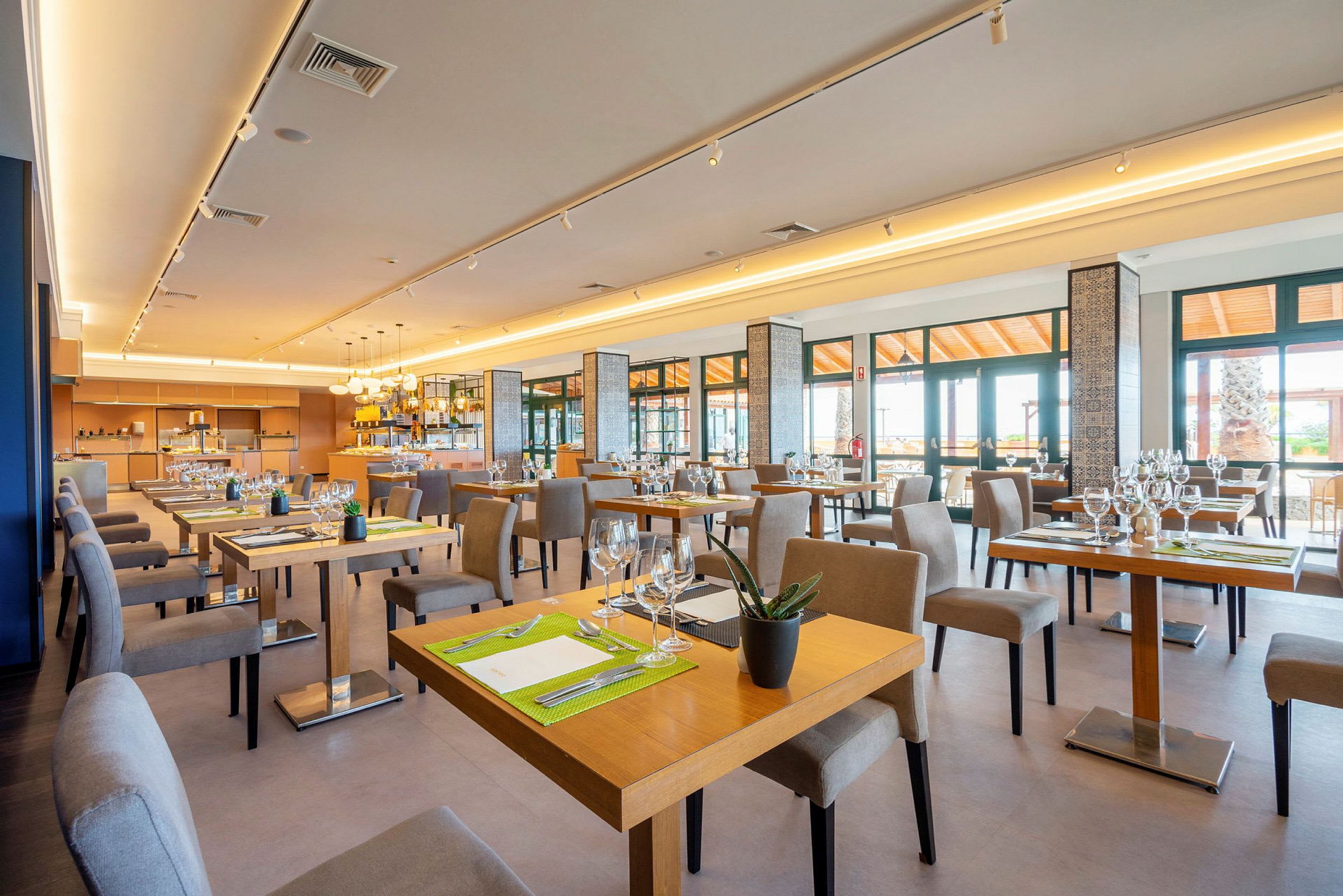 Billede af en lys og moderne restaurant med borde og stole. (AI-genereret tekst)