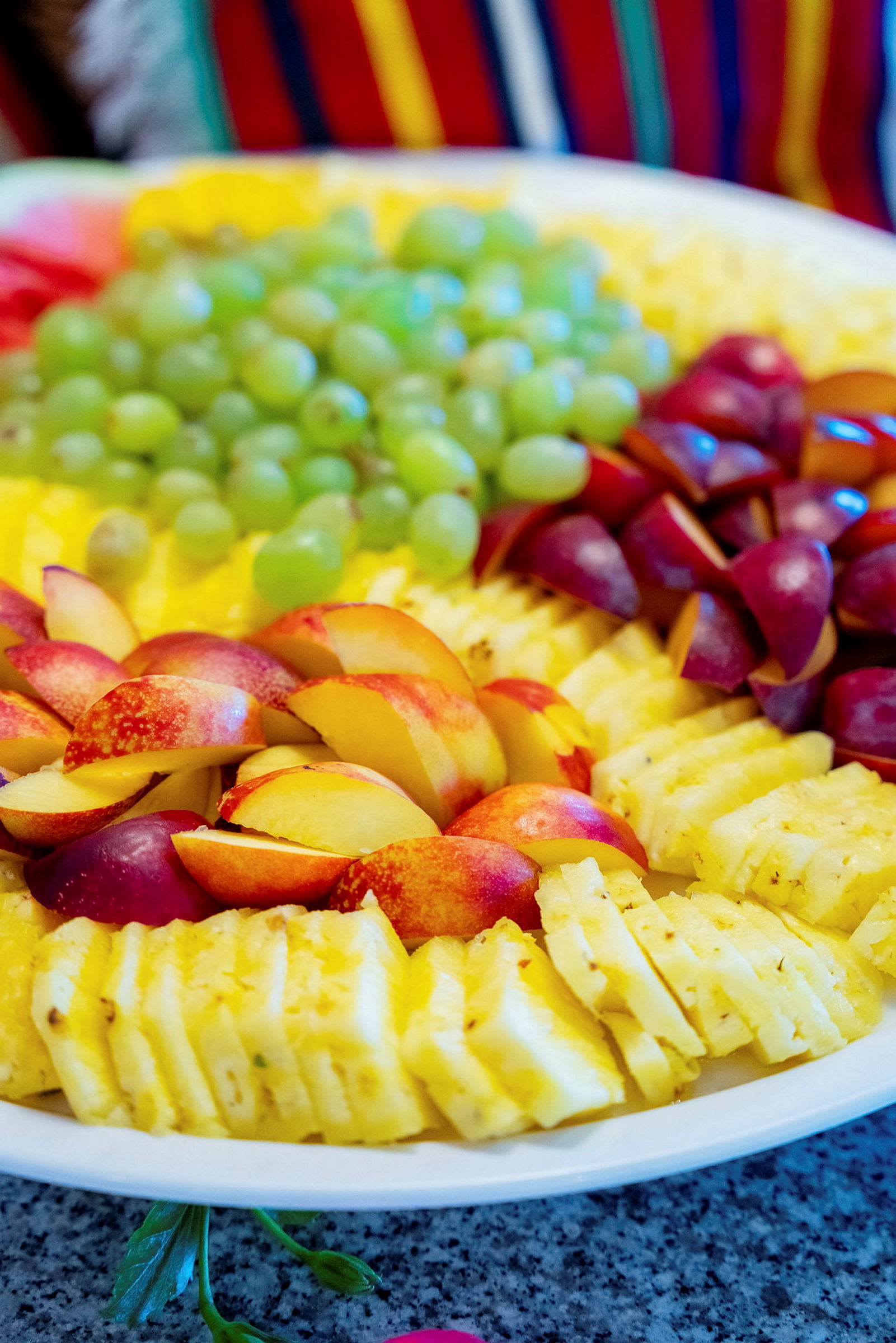 En tallerken med skåret ananas, druer, nektariner og røde frugter. (AI-genereret tekst)