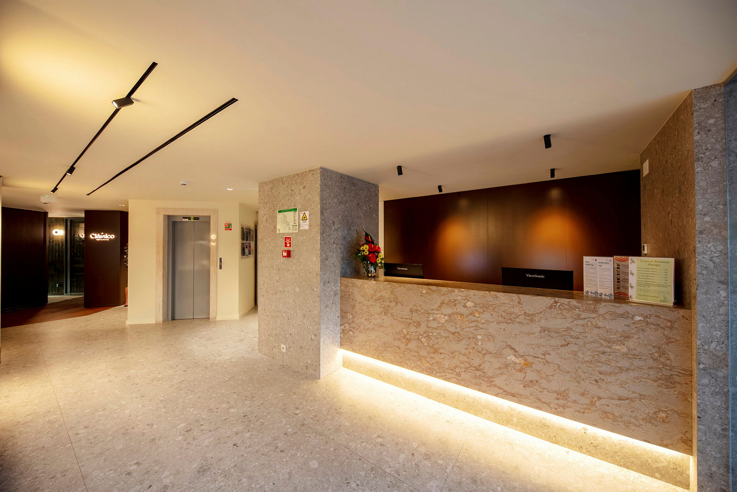 Billede af en hotelreception med marmordisk og elevator i baggrunden. (AI-genereret tekst)