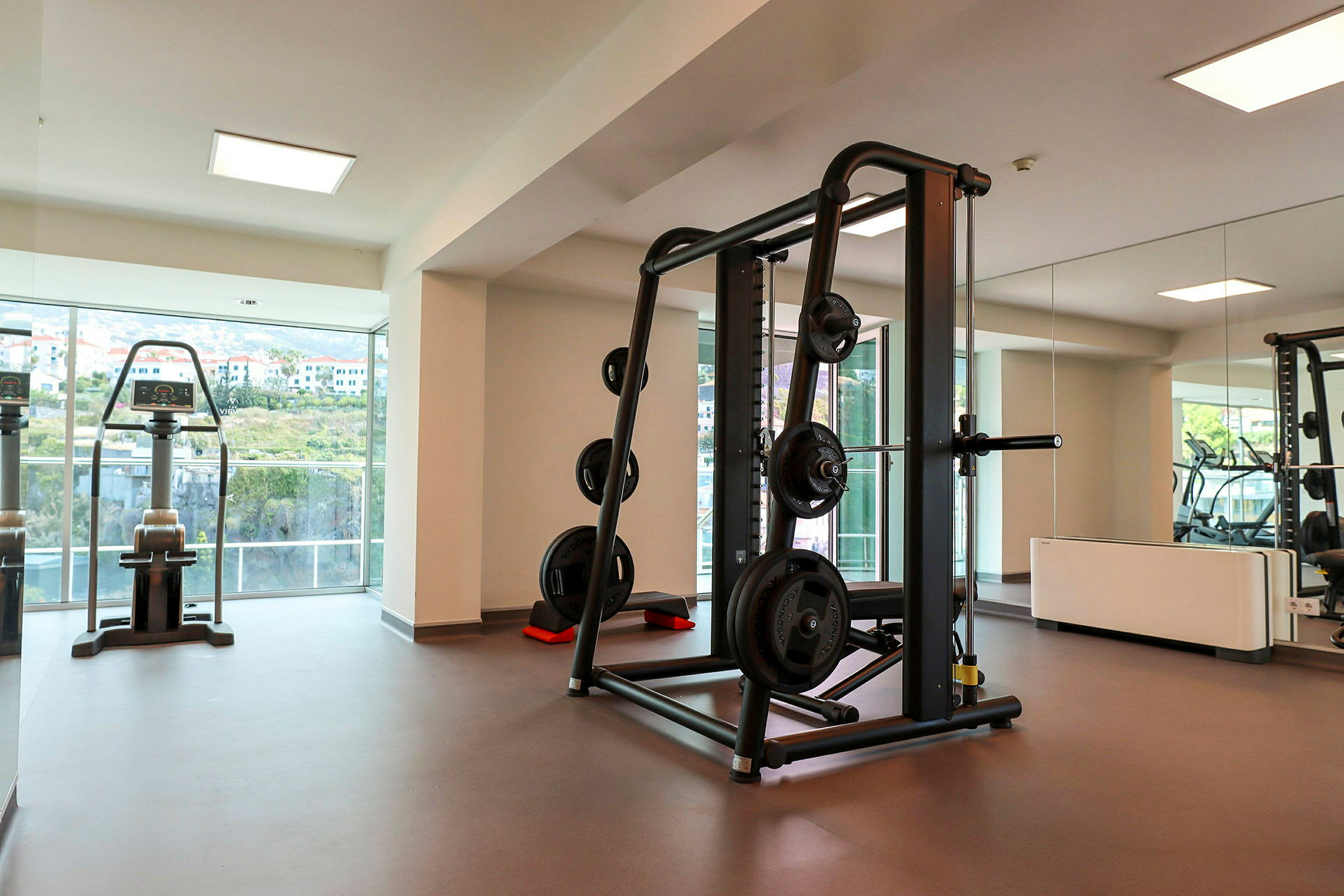 Et fitnesscenter med styrketræningsudstyr og vinduer med udsigt. (AI-genereret tekst)