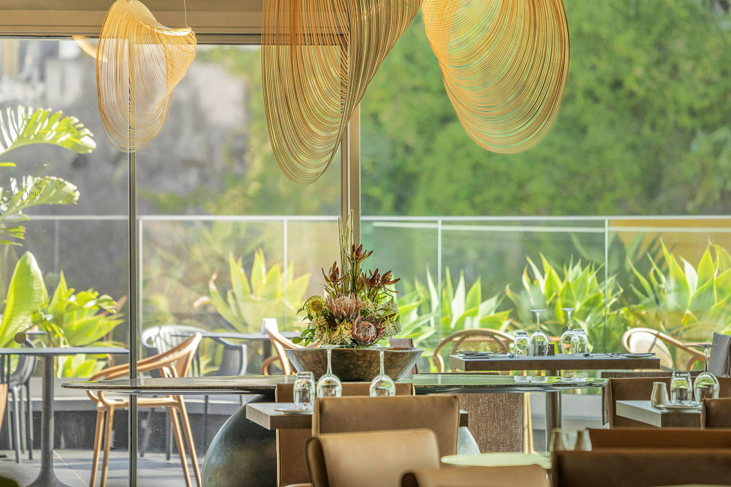 Et lyst og luftigt indrettet restaurantområde med glas og grønne planter. (AI-genereret tekst)