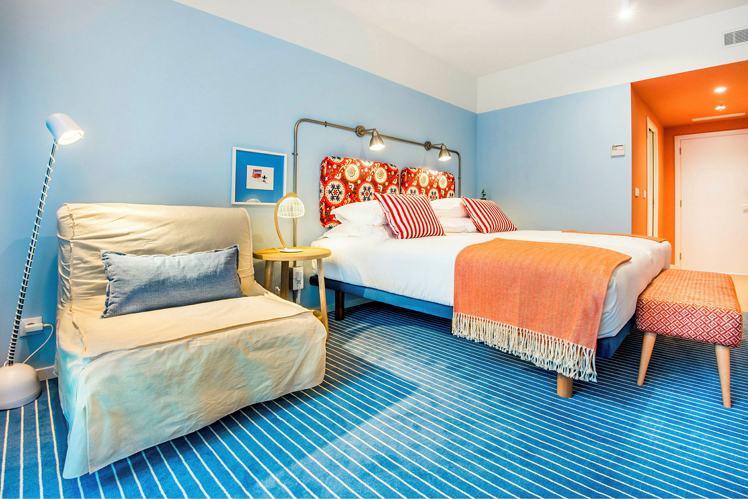 Et farverigt hotelværelse med en dobbelt seng og dekorative puder. (AI-genereret tekst)