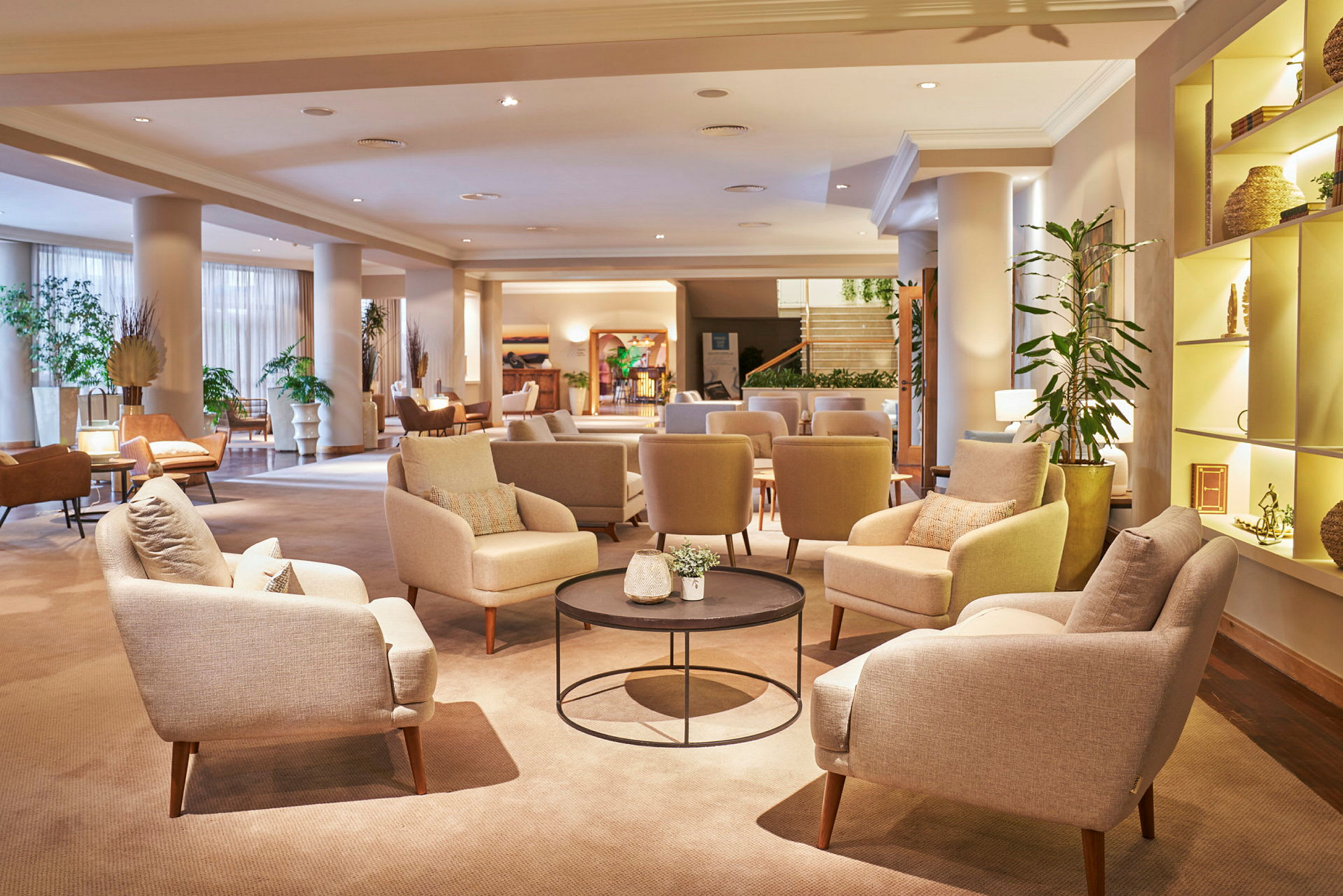 En hotellobby med komfortable stole og sofaer, borde med dekorationer og planter. (AI-genereret tekst)