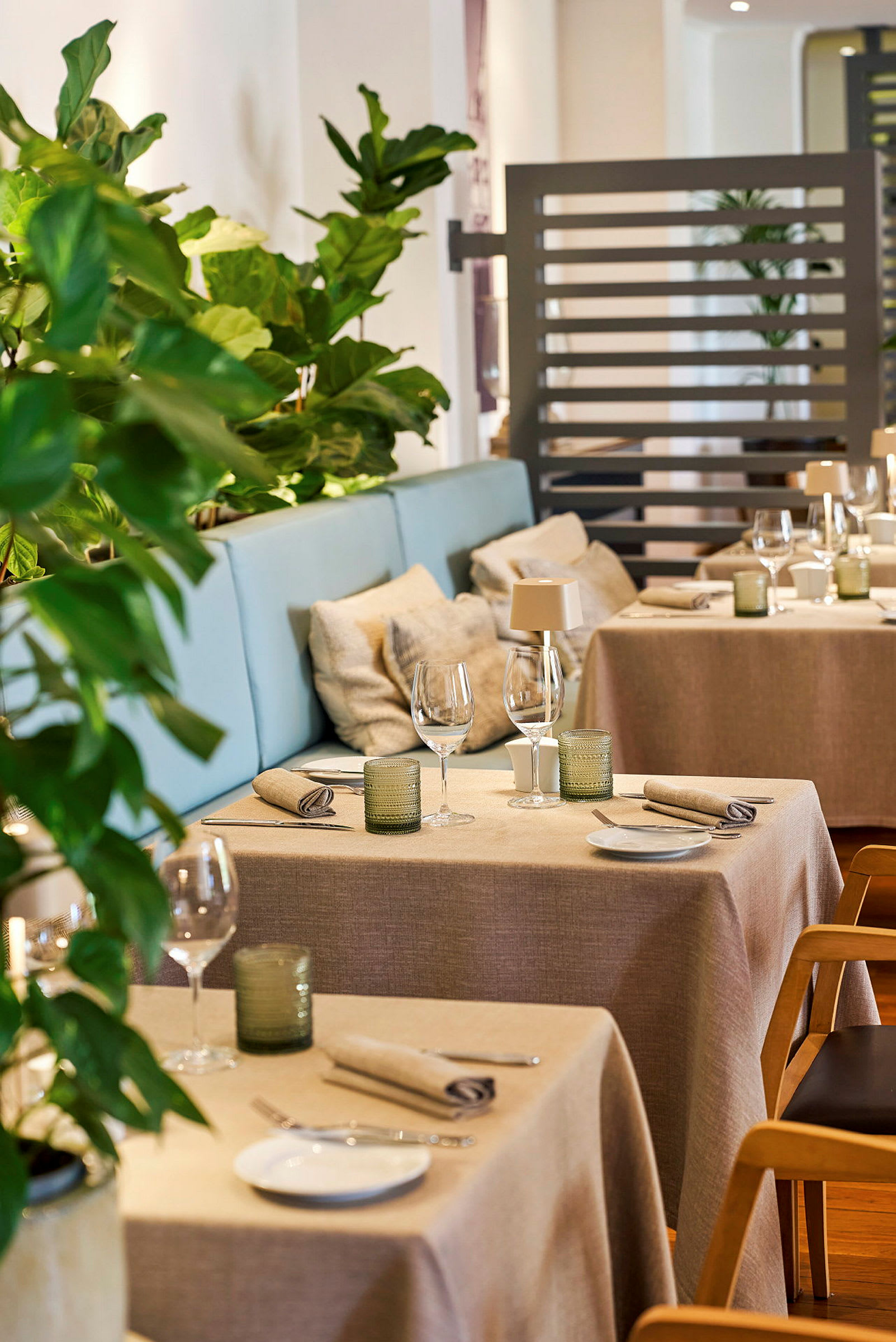 En elegant indrettet restaurant med duge, stofservietter og grønne planter. (AI-genereret tekst)
