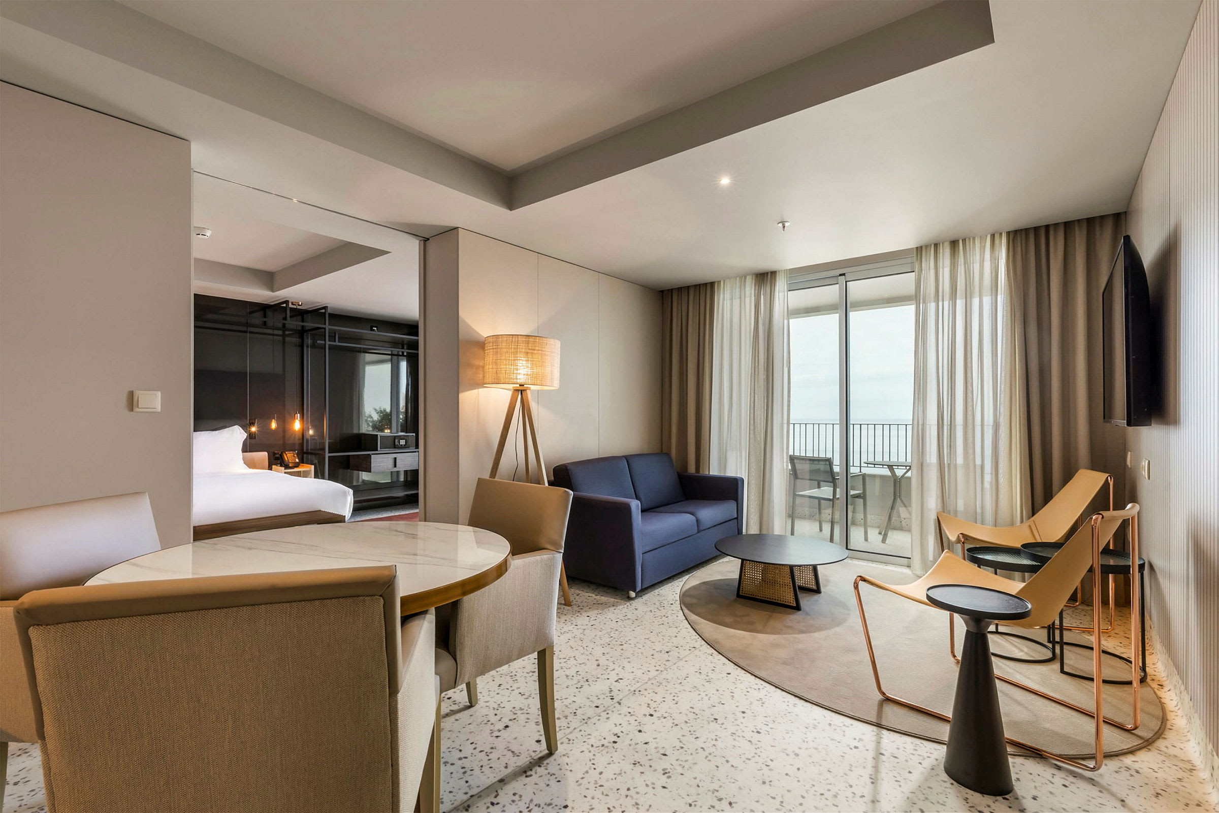 Et moderne hotelværelse med siddeområde, seng og udsigt til altanen. (AI-genereret tekst)