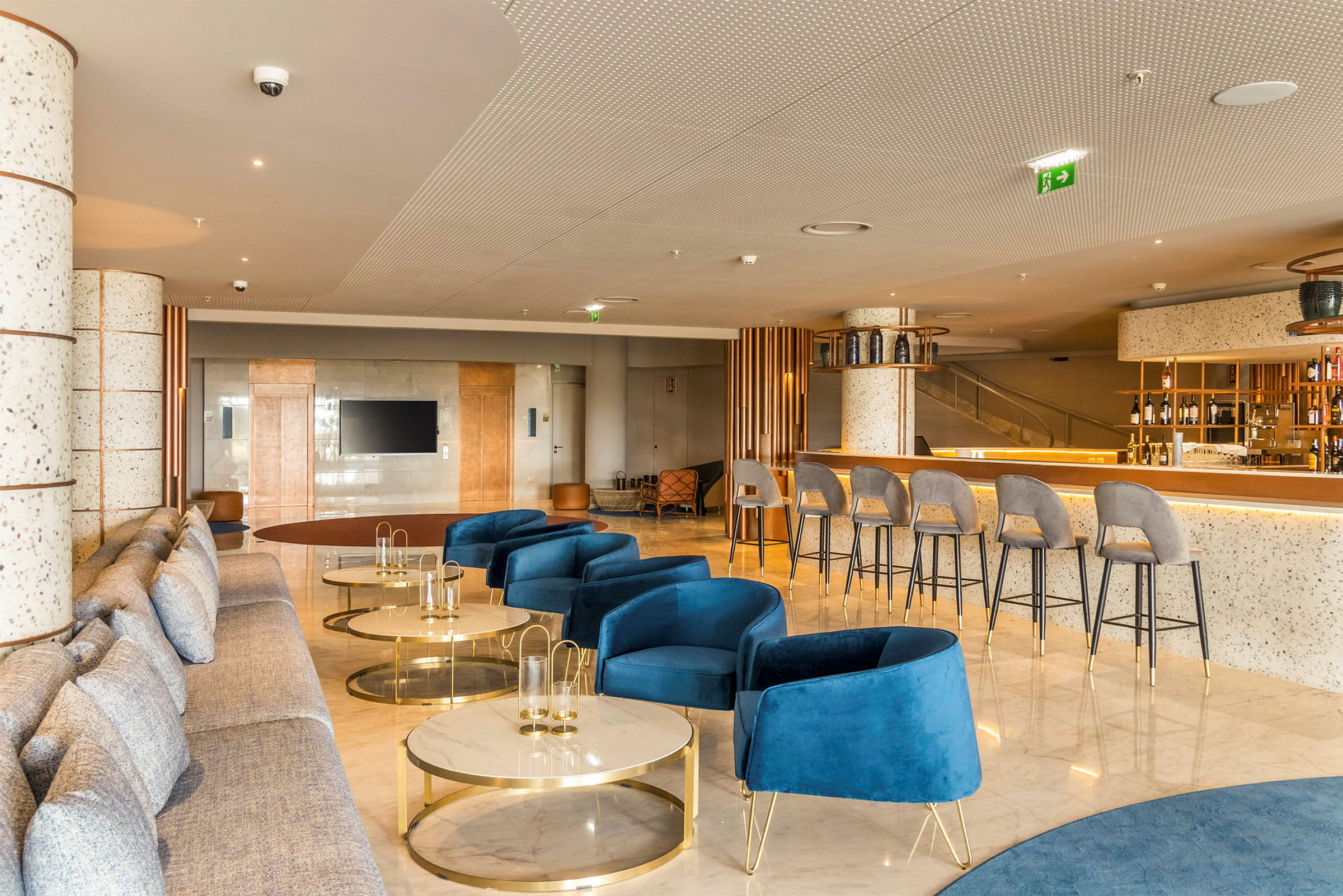 Moderne hotelværelse med blå stole, sofaer og et barområde. (AI-genereret tekst)