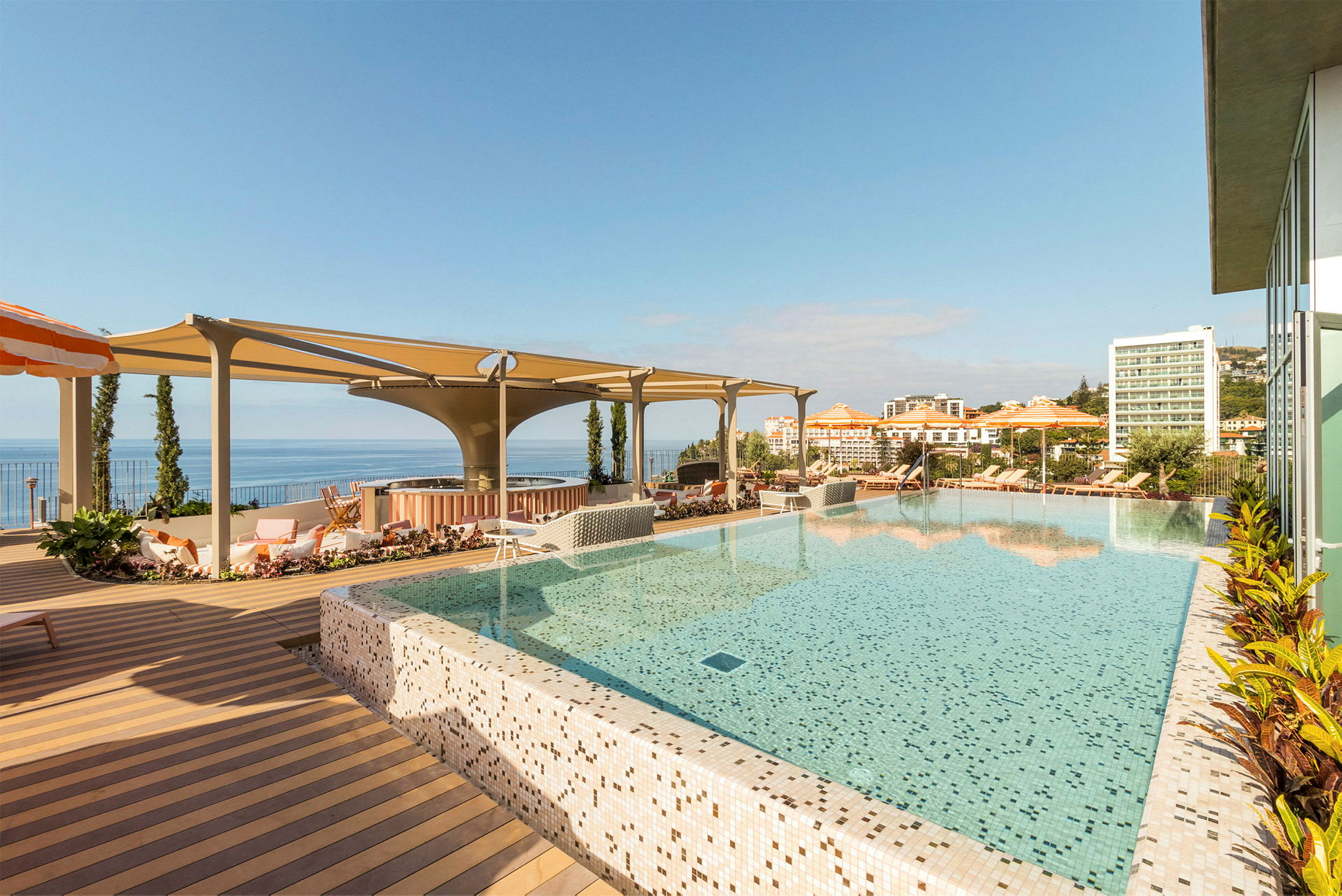 En infinity-pool med udsigt over havet og hotelbygninger i baggrunden. (AI-genereret tekst)