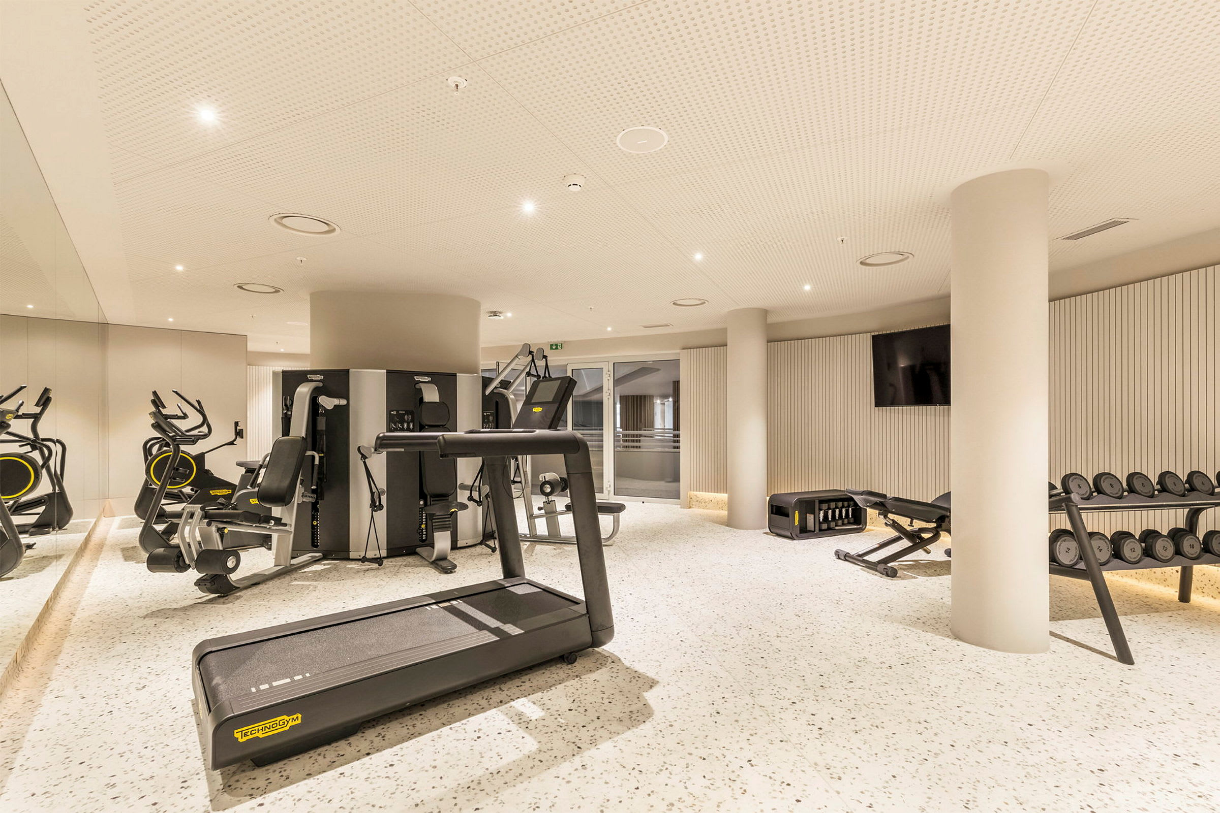 Et moderne fitnesscenter med træningsmaskiner, løbebånd og vægte. (AI-genereret tekst)