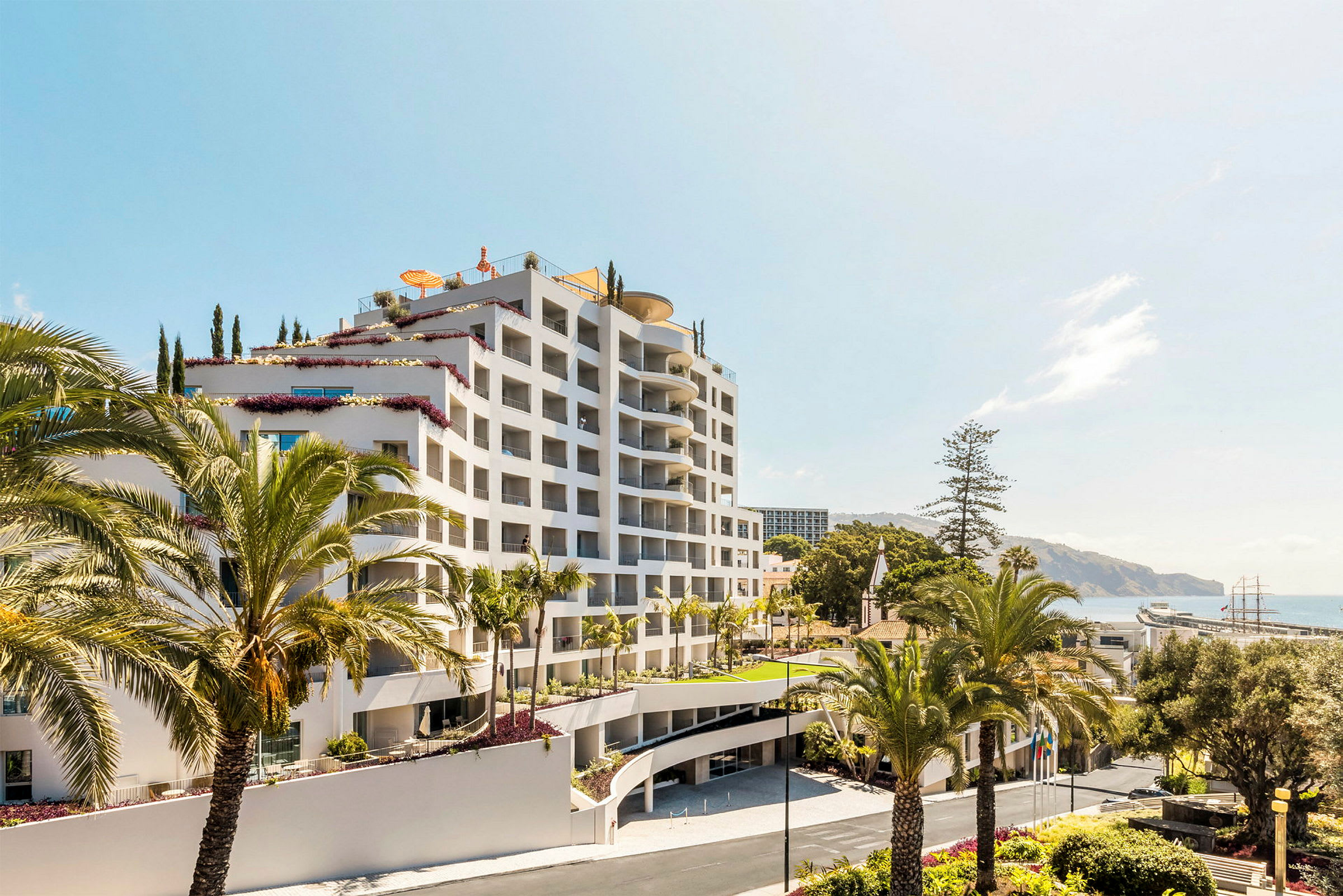 Et fler-etagers hotel omgivet af palmer, med havet i baggrunden. (AI-genereret tekst)
