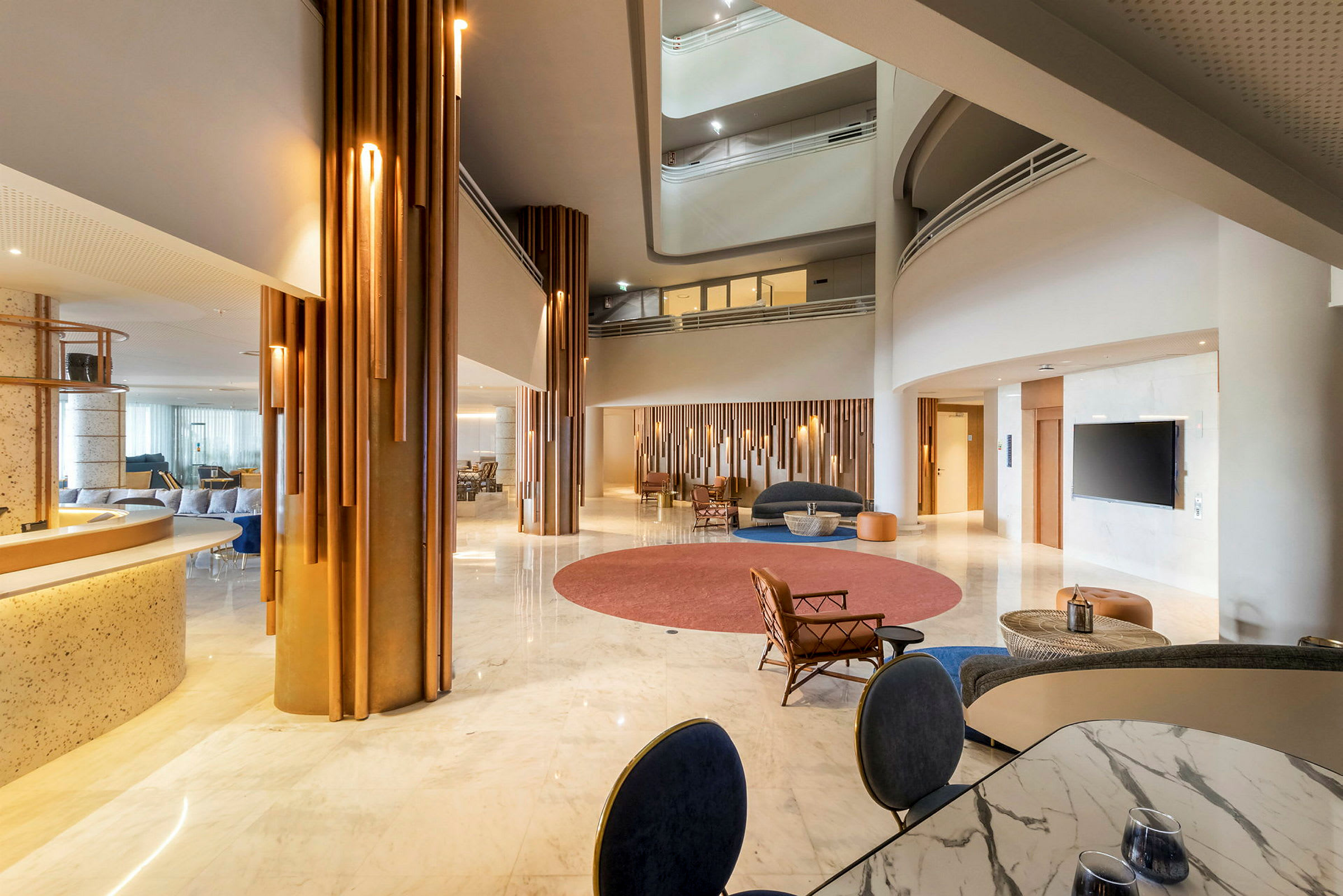 Lys og rummelig hotellobby med moderne indretning, siddegrupper og store glasflader. (AI-genereret tekst)