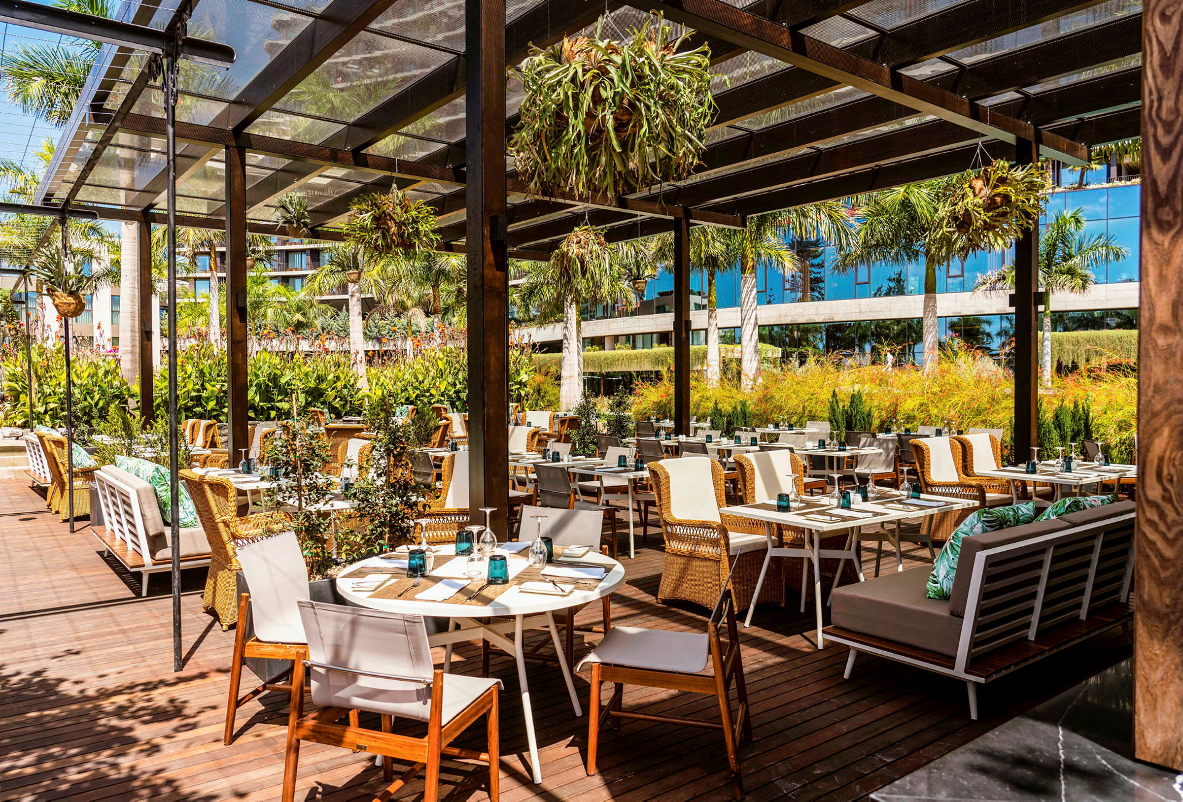 Udendørsrestaurant med træborde og stole under en pergola. (AI-genereret tekst)