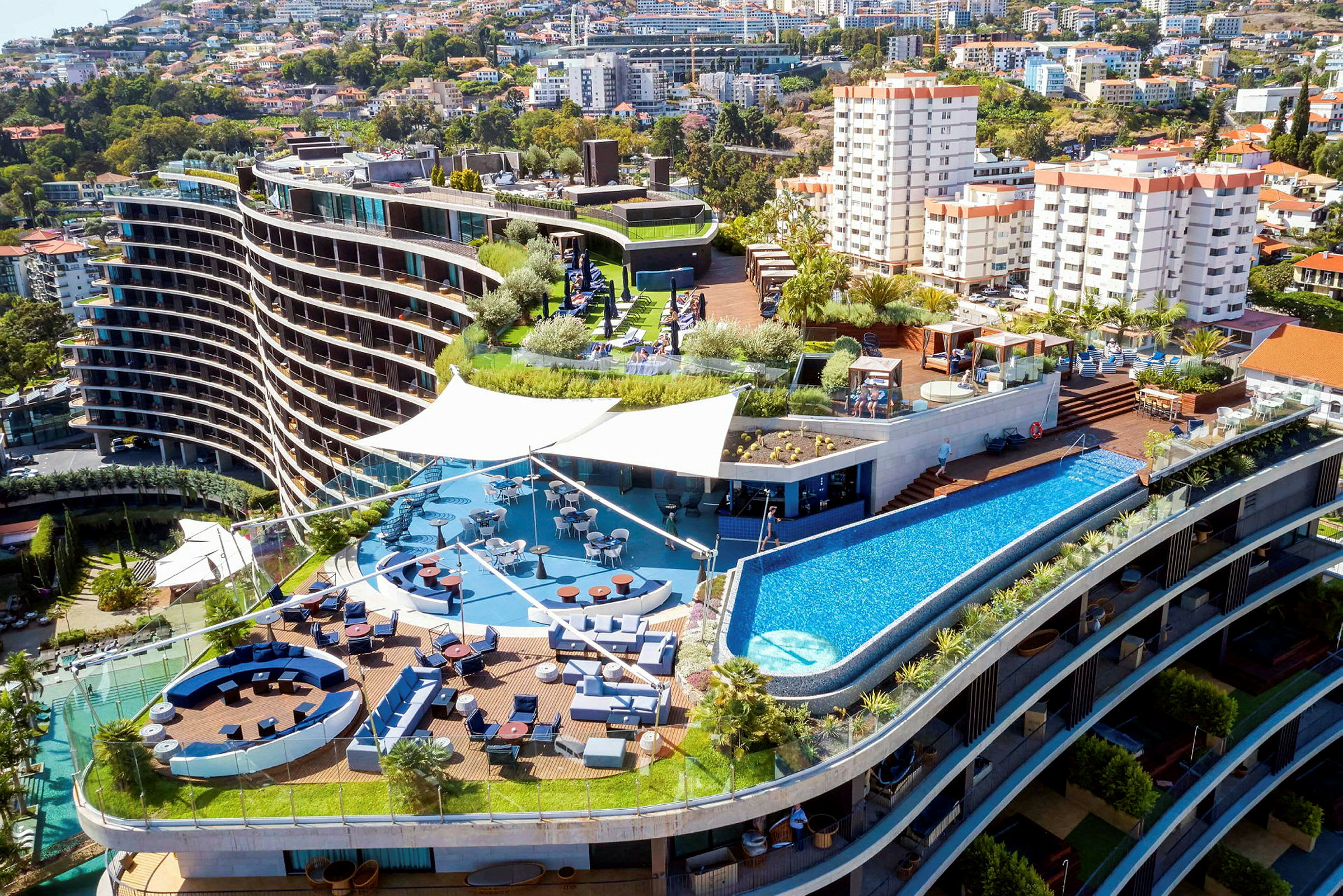 Hotelkompleks med terrasse, pool og siddeområder. (AI-genereret tekst)
