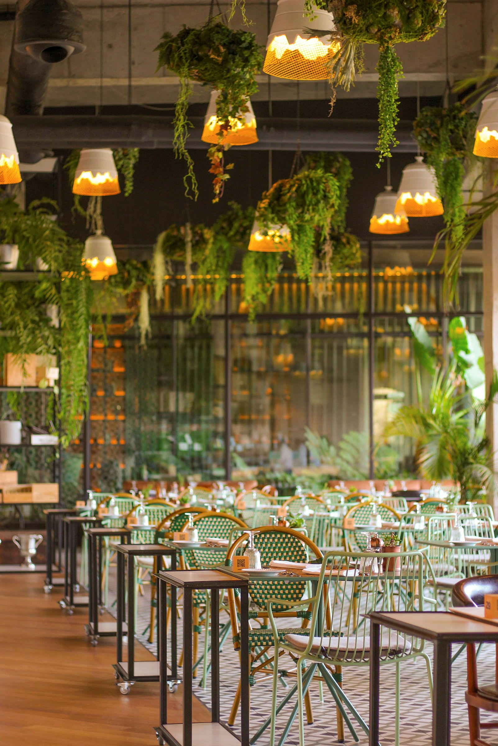 Interiør af en restaurant med grønne siddepladser og planter i loftet. (AI-genereret tekst)