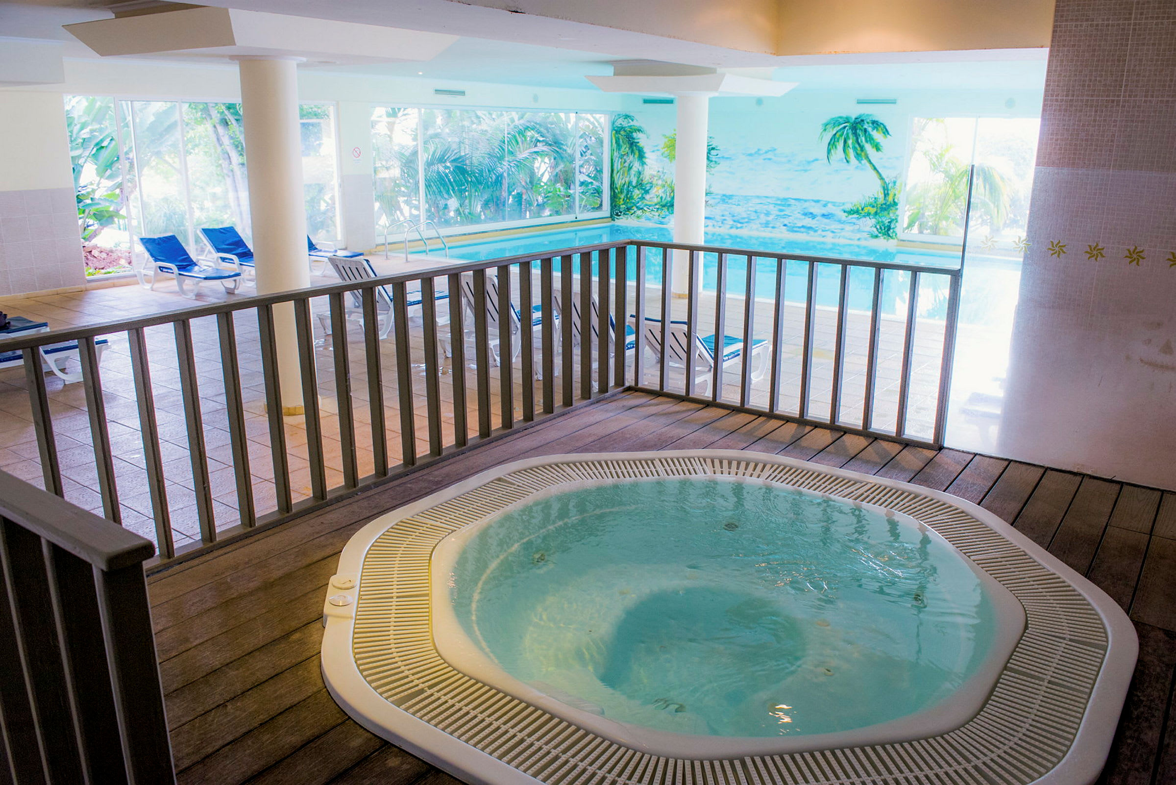 Interiør med en jacuzzi og en pool samt liggestole i baggrunden. (AI-genereret tekst)