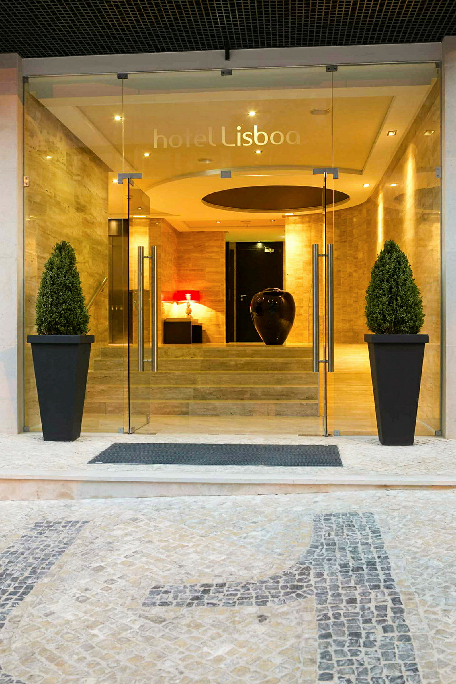 Indgangen til hotellet Lisboa med glasdøre og dekorationer. (AI-genereret tekst)