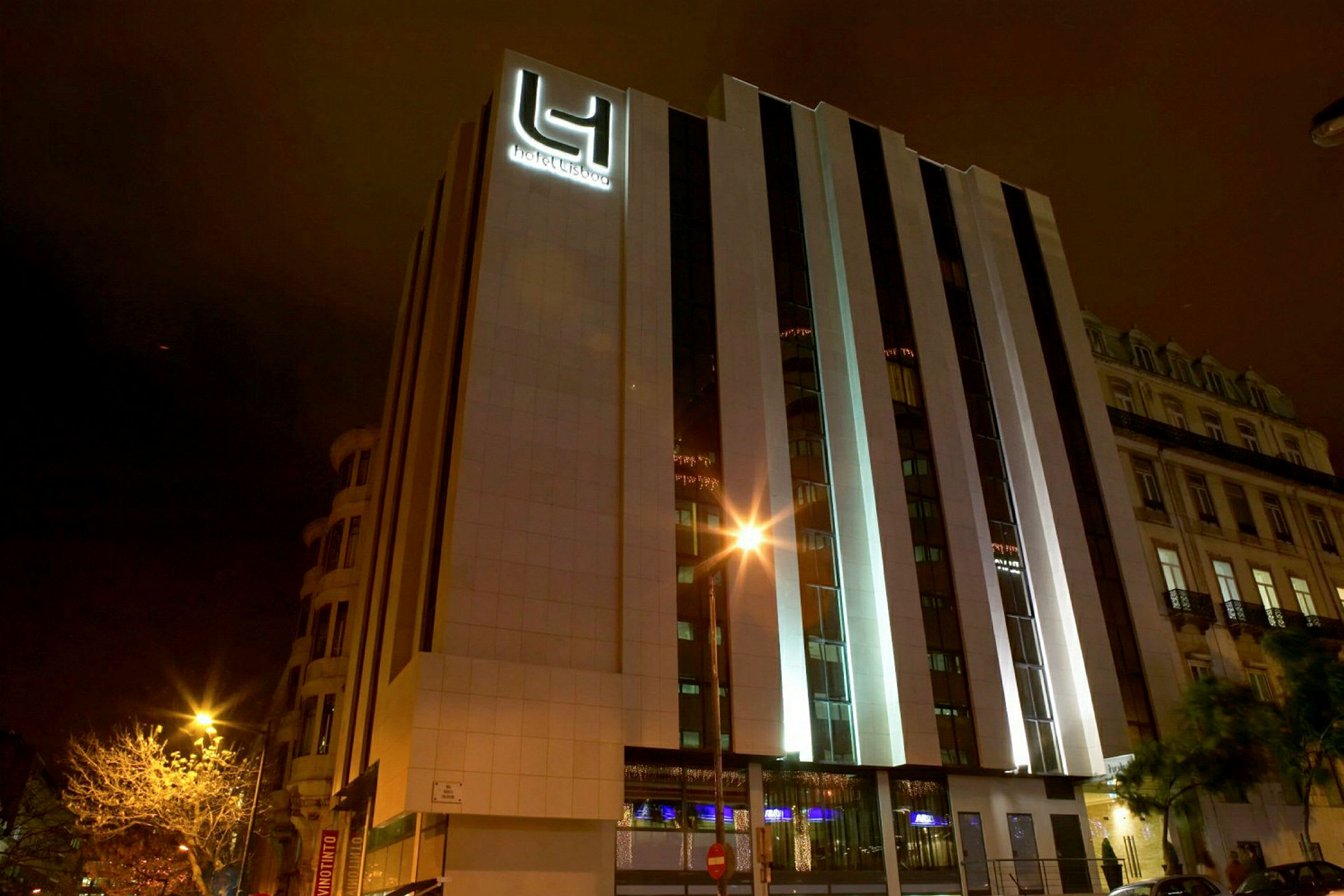 Et hotel med moderne ydre fotograferet om natten. Bygningens facade er oplyst. (AI-genereret tekst)