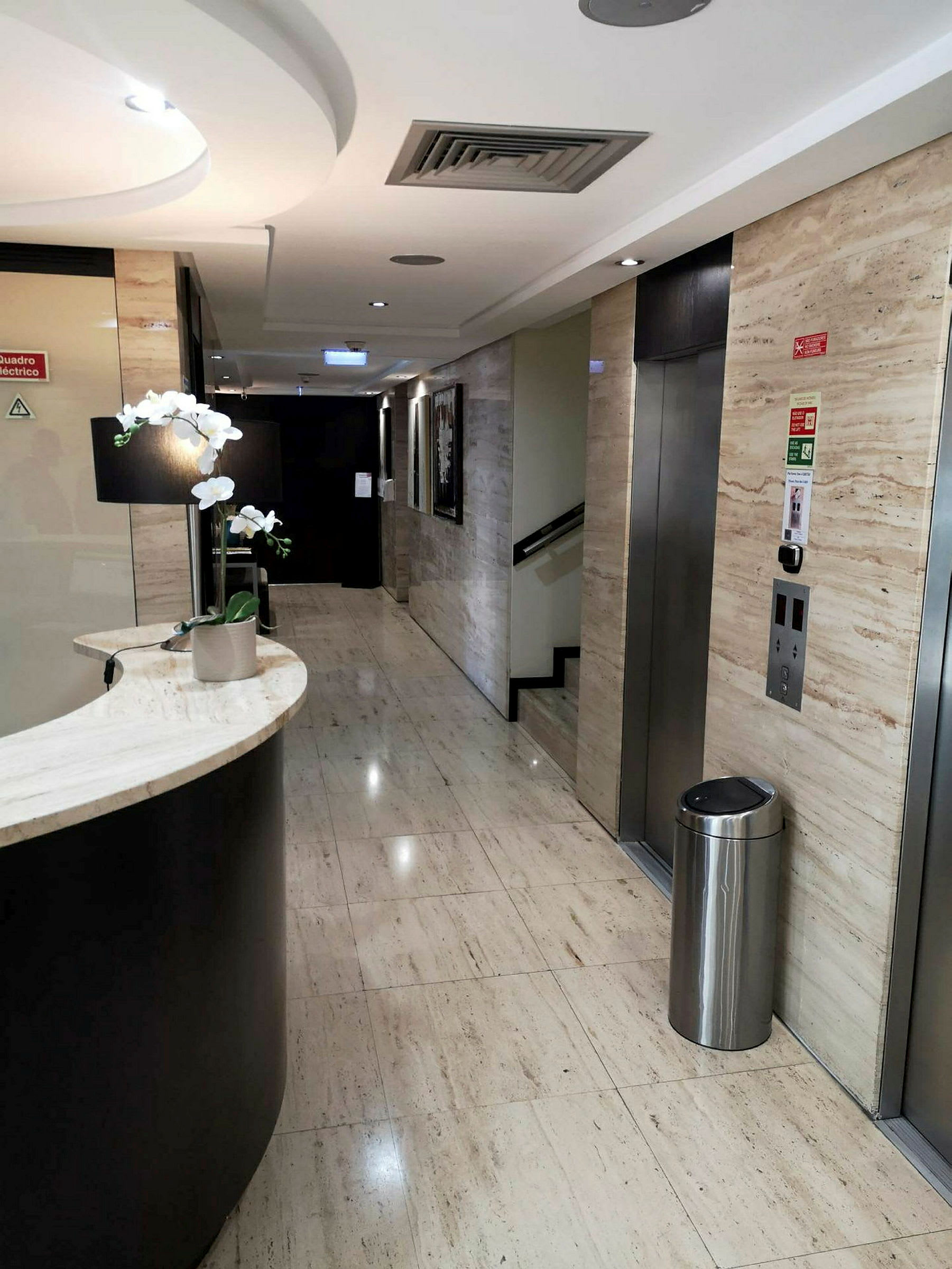 En moderne hotelkorridor med elevator og concierge-reception. (AI-genereret tekst)