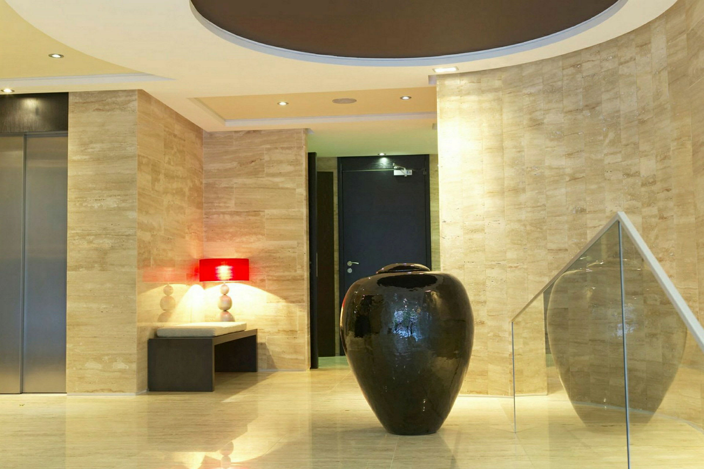 En hotellobby med en stor sort dekorativ vase i forgrunden, omgivet af marmordetaljer og moderne design. (AI-genereret tekst)
