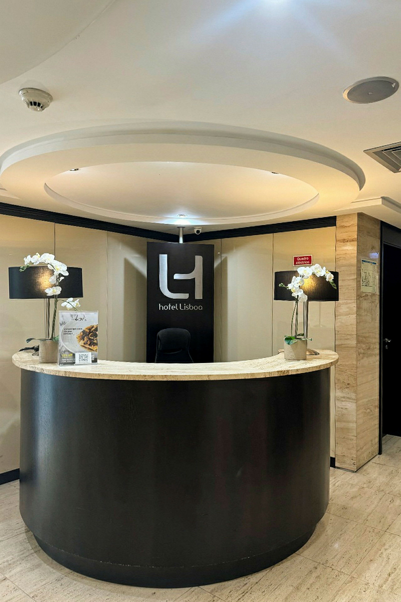 Receptionen på Hotel Lisboa med en sort skranke og dekorationer. (AI-genereret tekst)