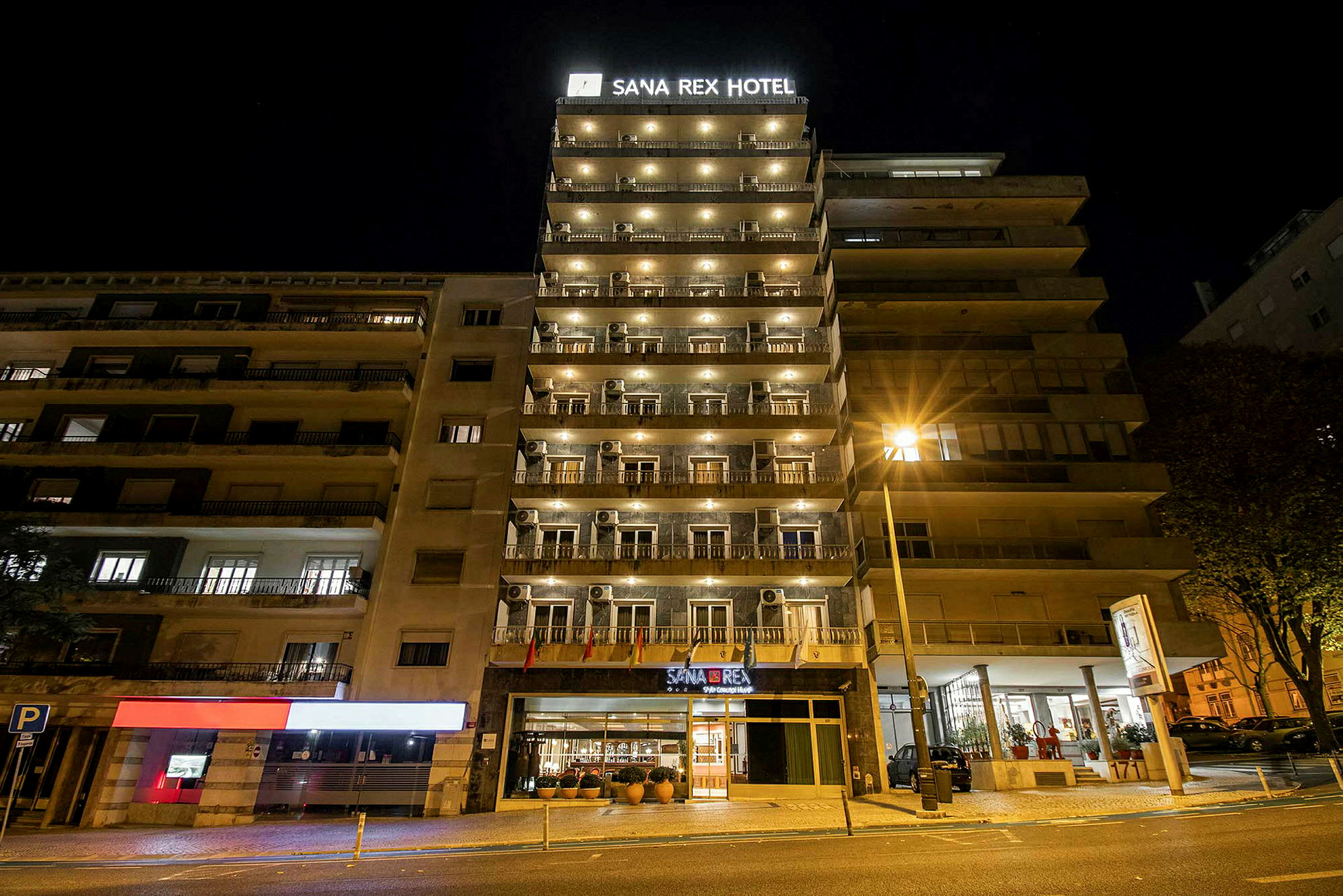 Billede af hotellet Sana Rex Hotel om natten, med facaden oplyst. (AI-genereret tekst)