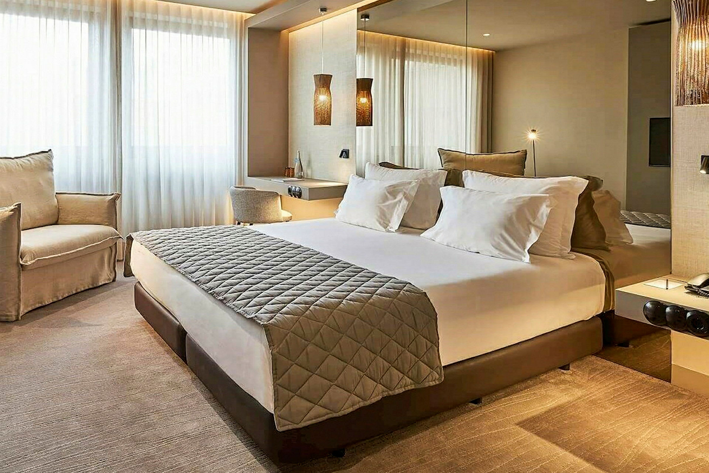 Et moderne hotelværelse med en dobbeltseng, to stole og et skrivebord. (AI-genereret tekst)