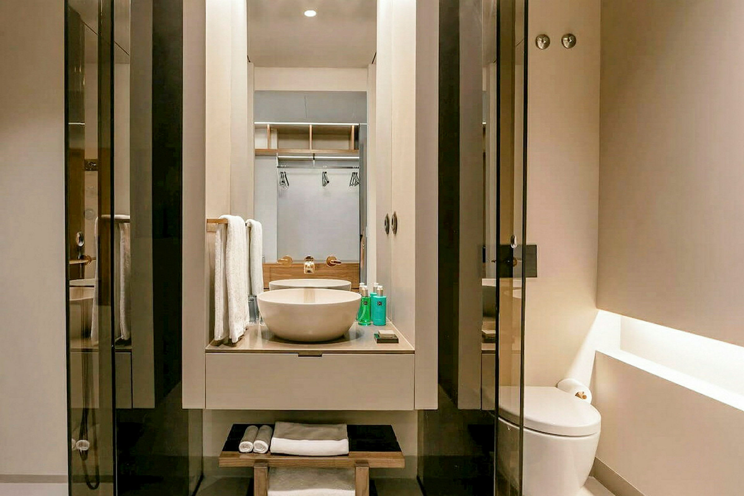 Et moderne badeværelse med en cirkelformet håndvask, spejl og toilet. (AI-genereret tekst)