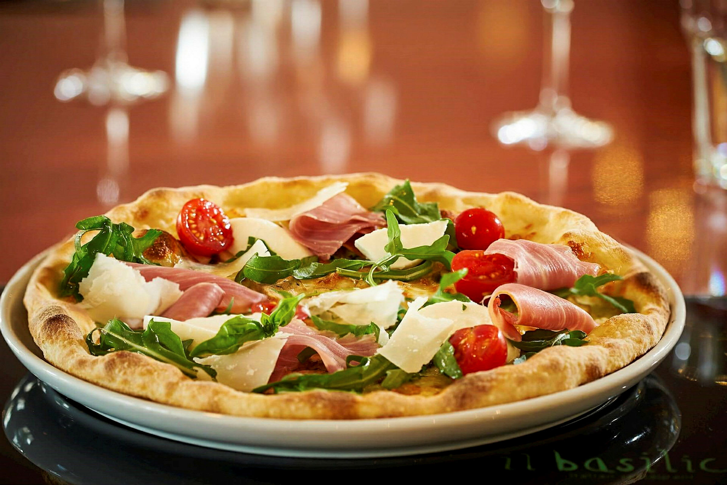 En pizza med cherrytomater, rucola, parmesan og skinke. (AI-genereret tekst)