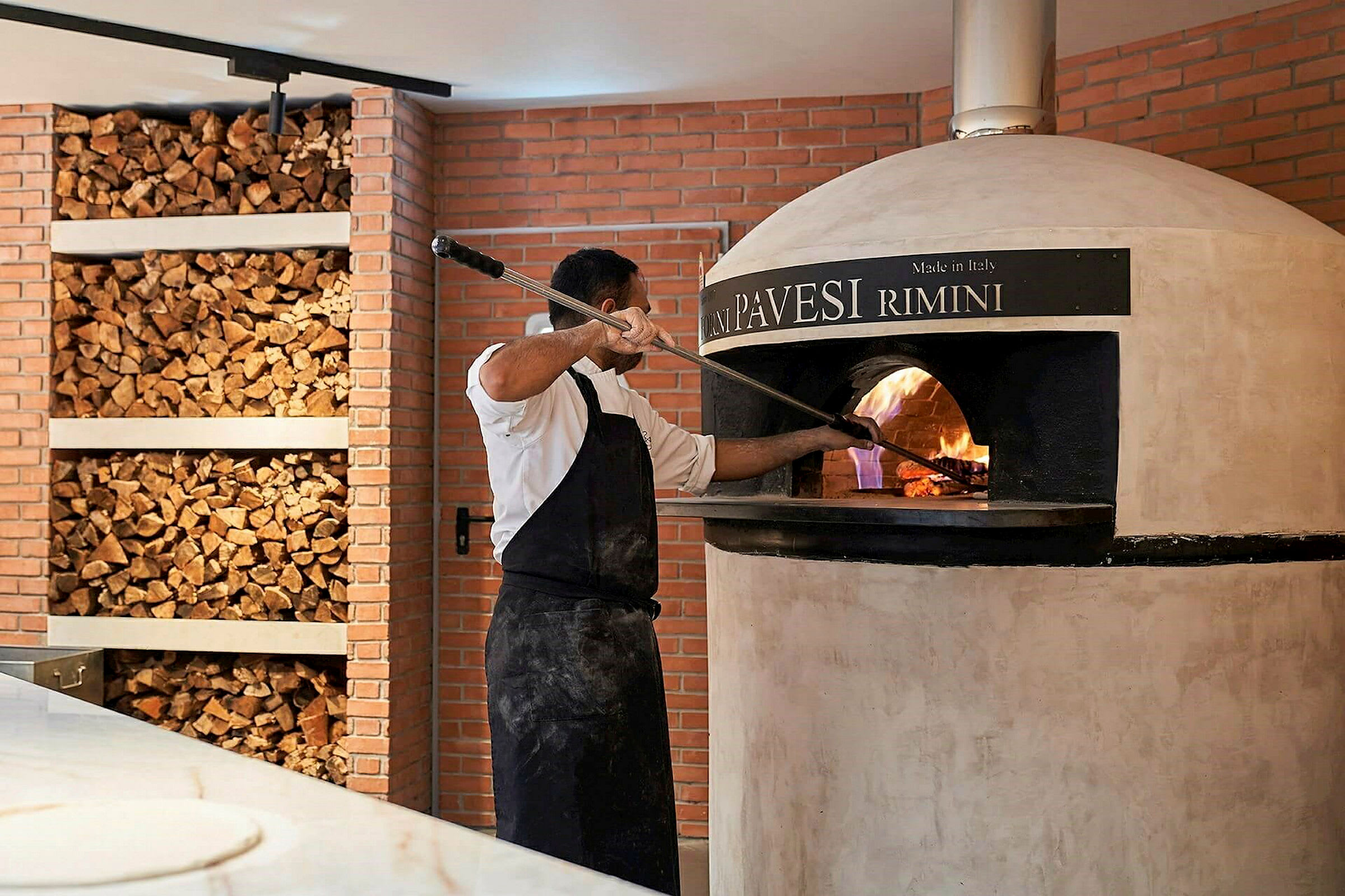 Personen bager pizza i en brændefyret ovn. (AI-genereret tekst)