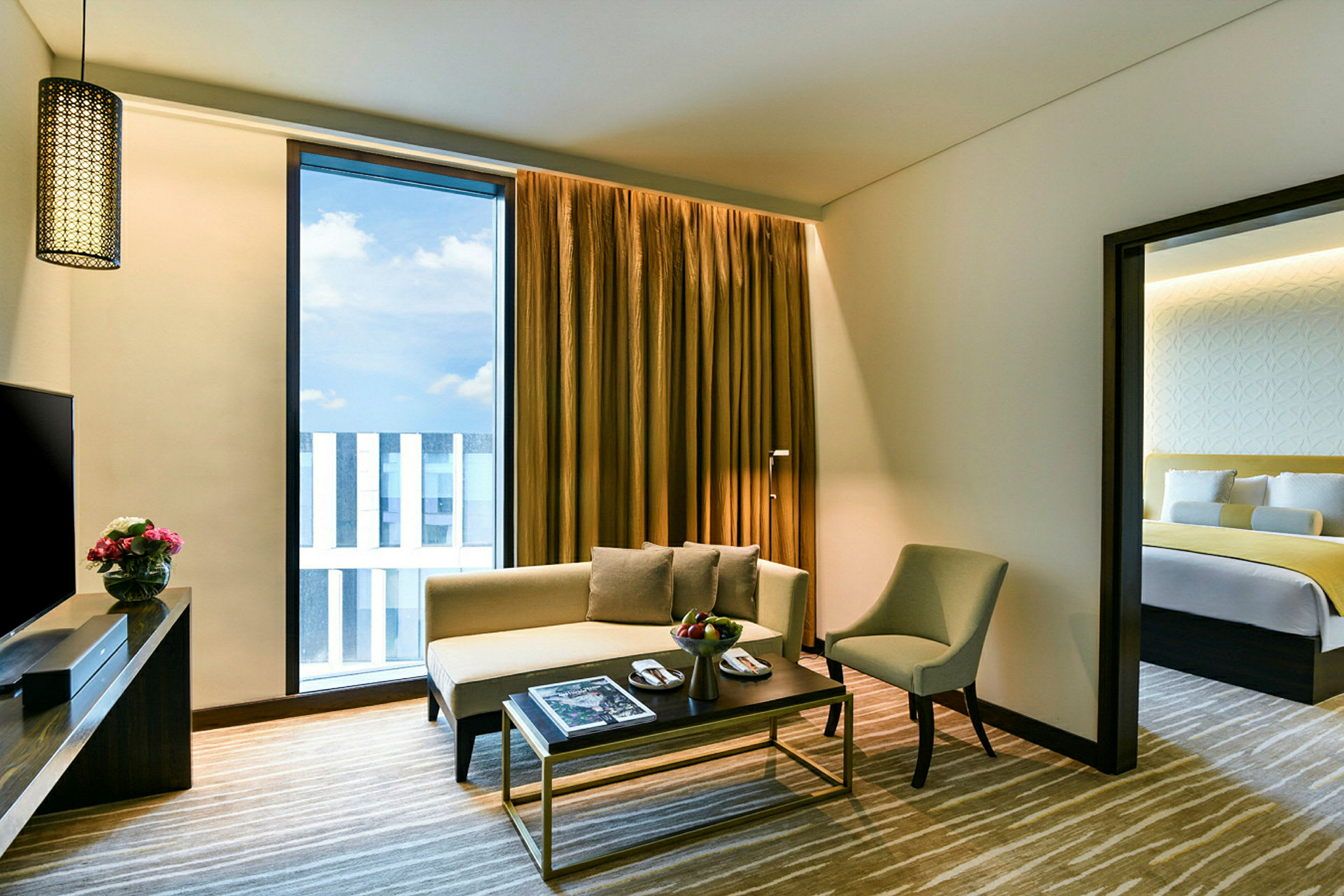 Et moderne og lyst hotelværelse med en stue og en dør, der fører til et soveværelse. (AI-genereret tekst)