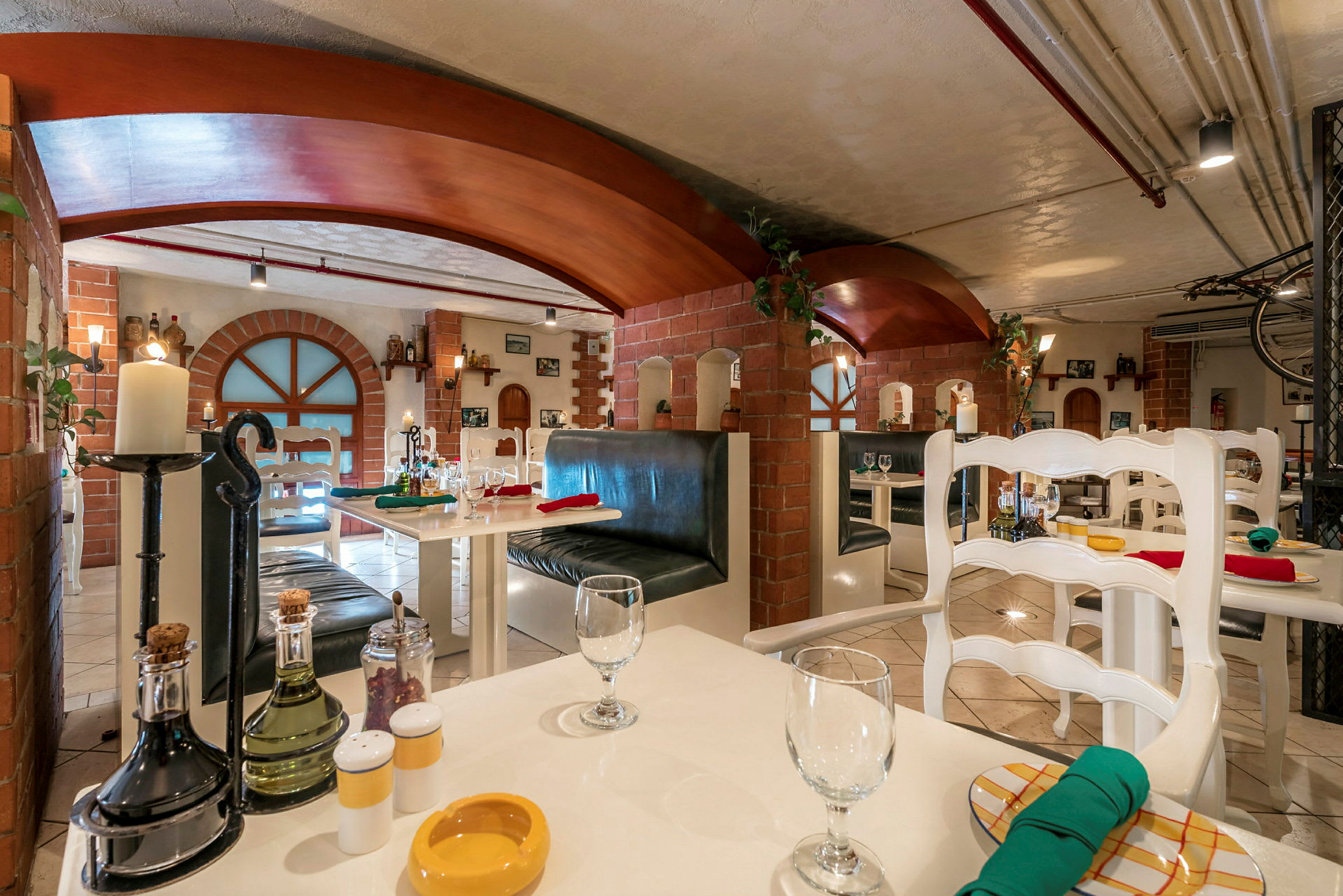 En interiør af en restaurant med hvide borde, stole og murstensvægge. (AI-genereret tekst)