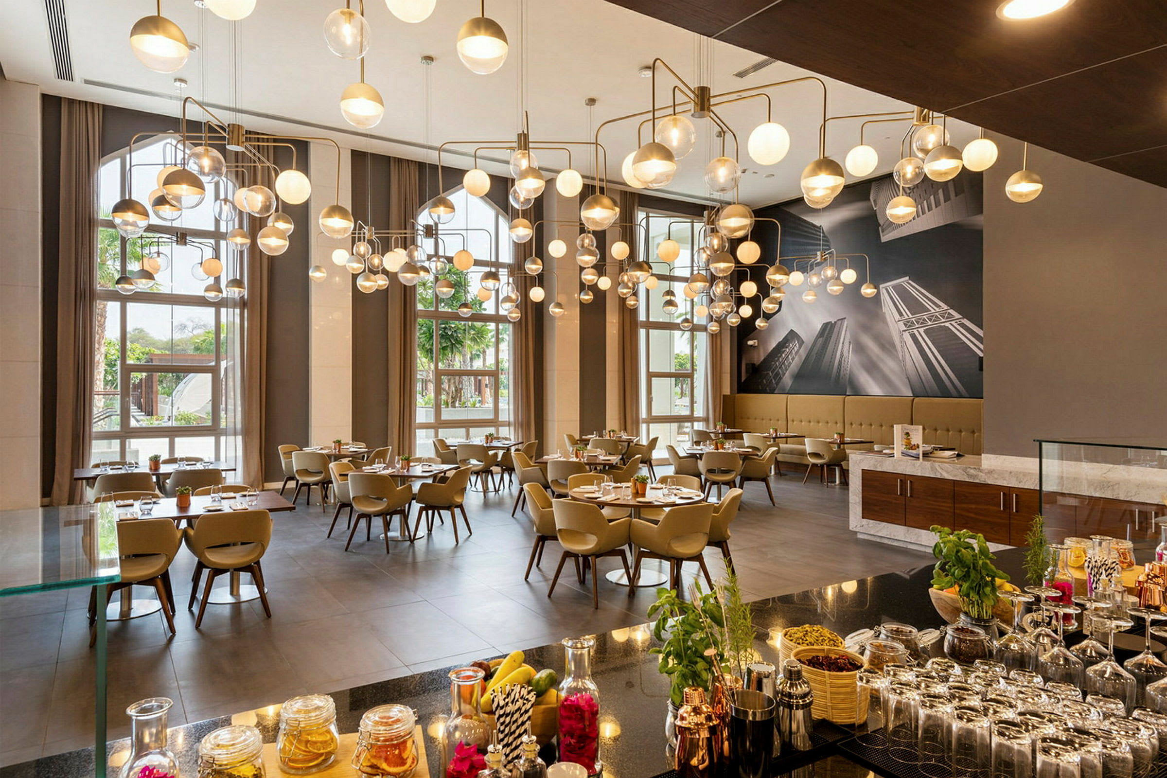 En elegant restaurant med moderne hængelamper, dækkede borde og store vinduer, der lukker naturligt lys ind. (AI-genereret tekst)