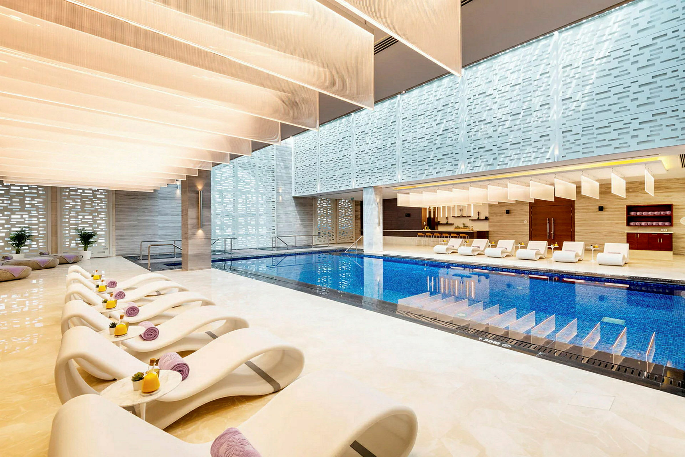 Indendørs pool med moderne hvide liggestole og stilfuldt design. (AI-genereret tekst)