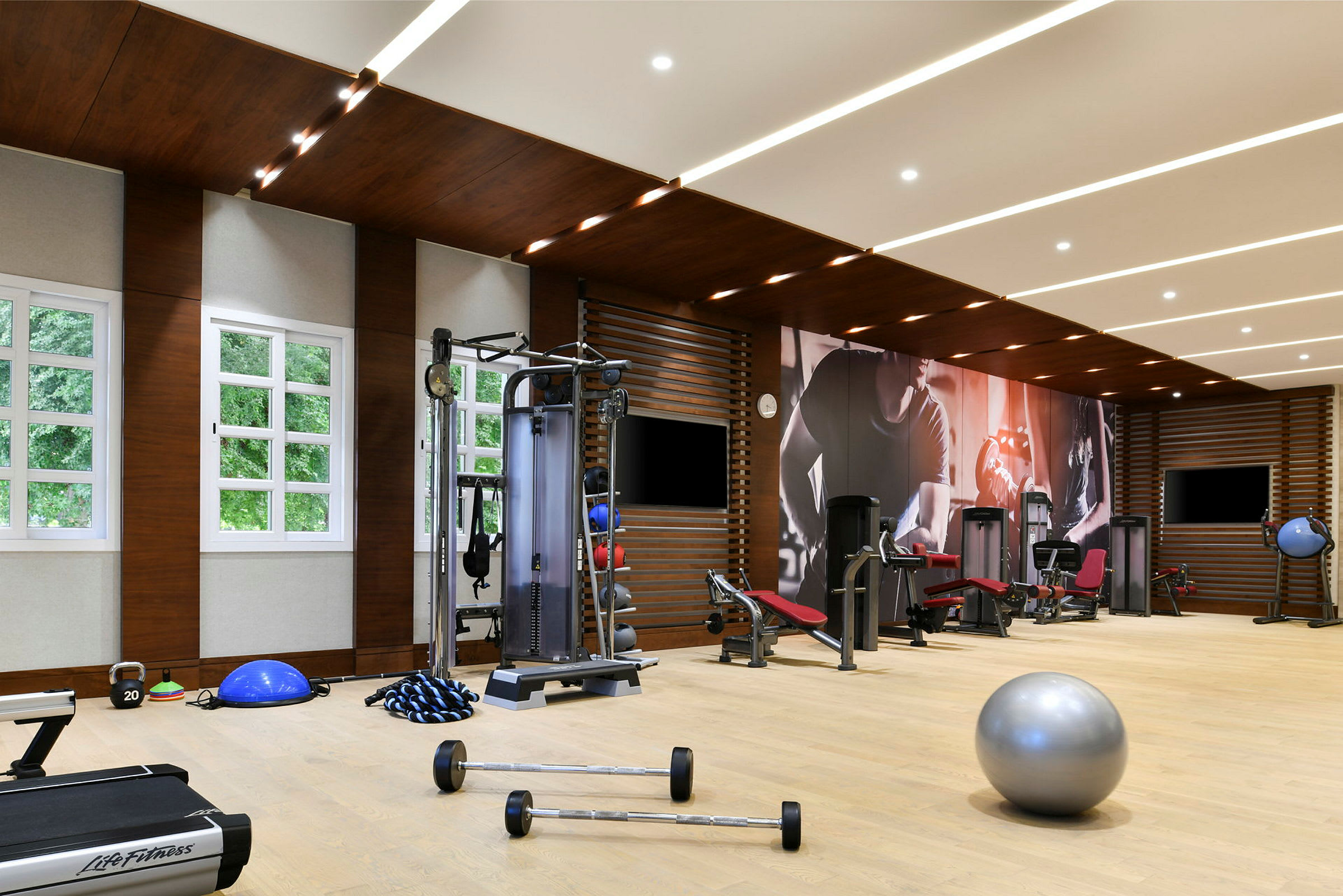 Et fitnesscenter med træningsudstyr og maskiner samt lyse vinduer. (AI-genereret tekst)